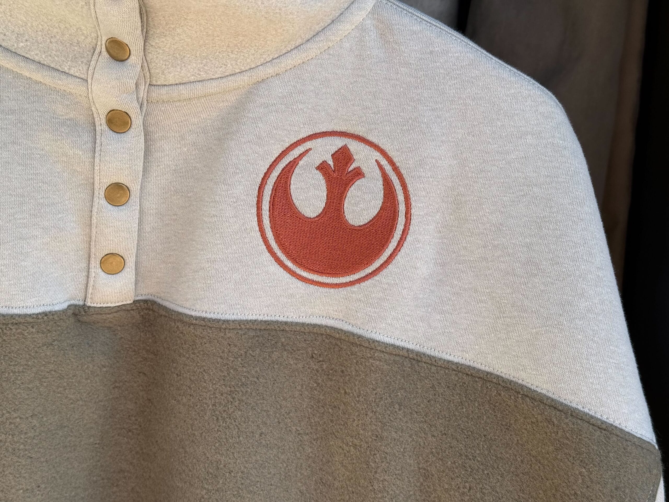 Light gray and beige pullover with Rebel symbol and gold buttons—perfect Star Wars merch from Galaxy's Edge.