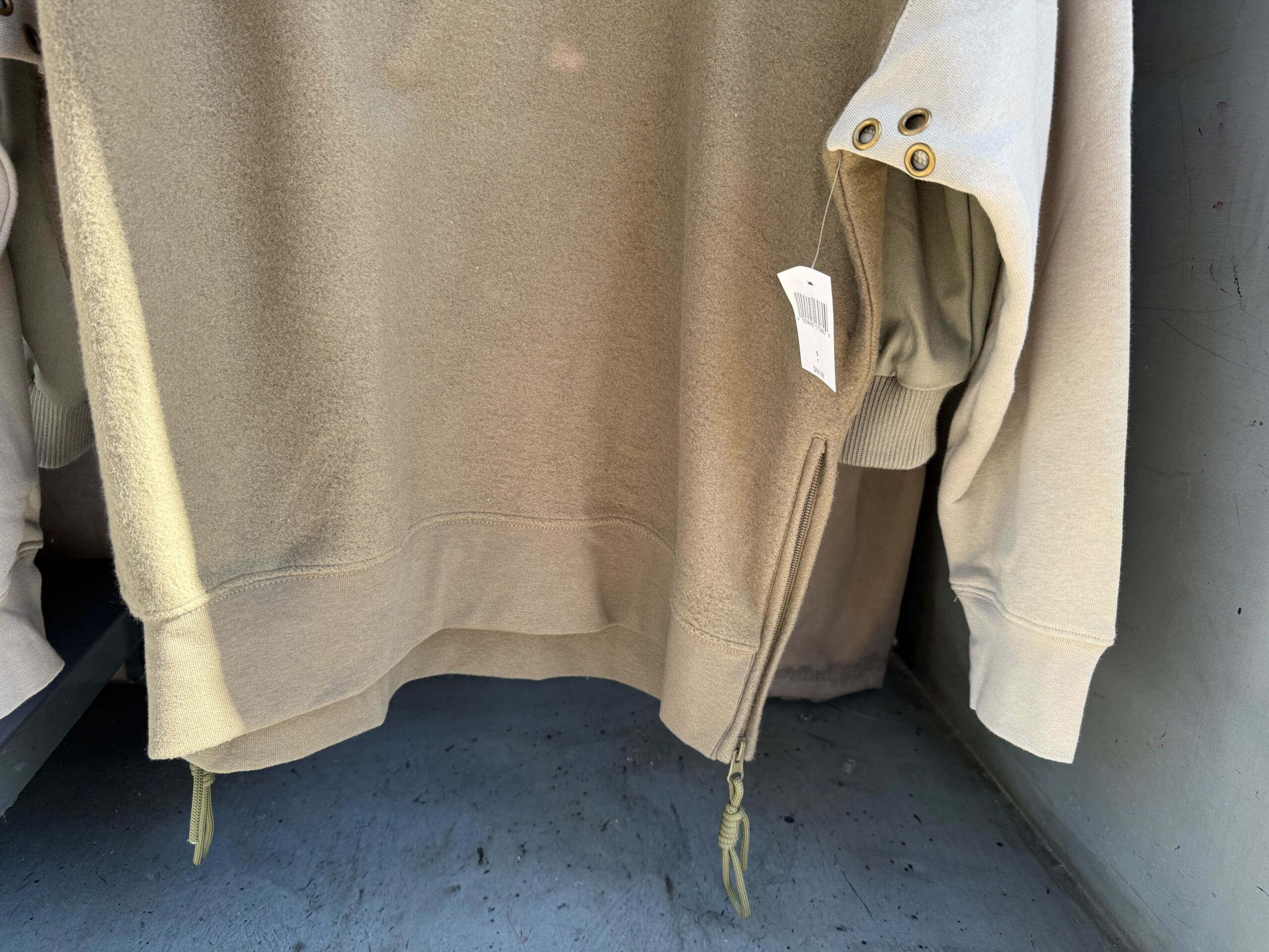 A beige sweatshirt with gold grommets and drawstrings hangs like Star Wars merch at Galaxy's Edge.