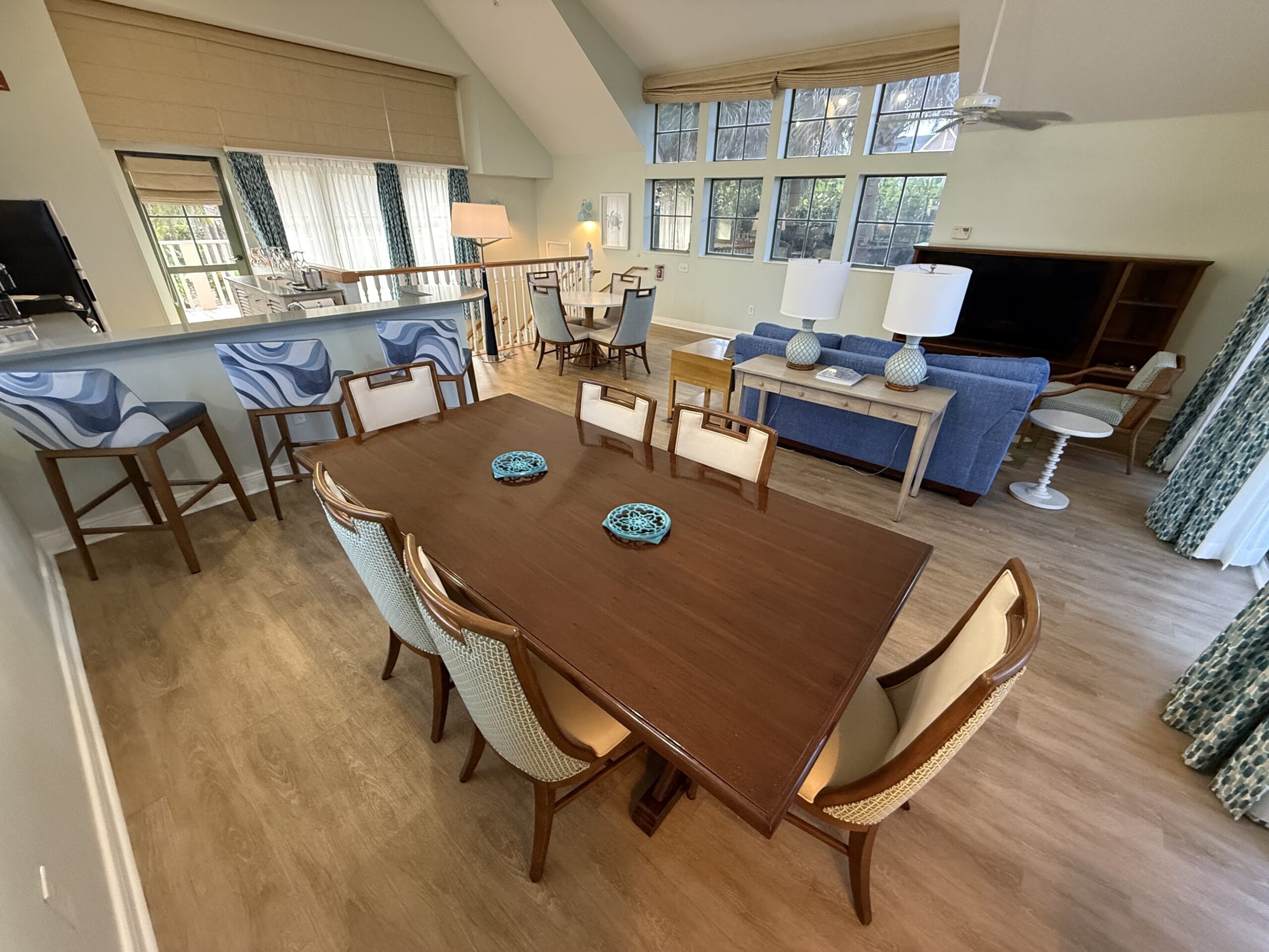 Open-concept living/dining space in a 3 Bedroom Cottage at Disney’s Vero Beach Resort, blue sofa, large windows, Disney ambiance.