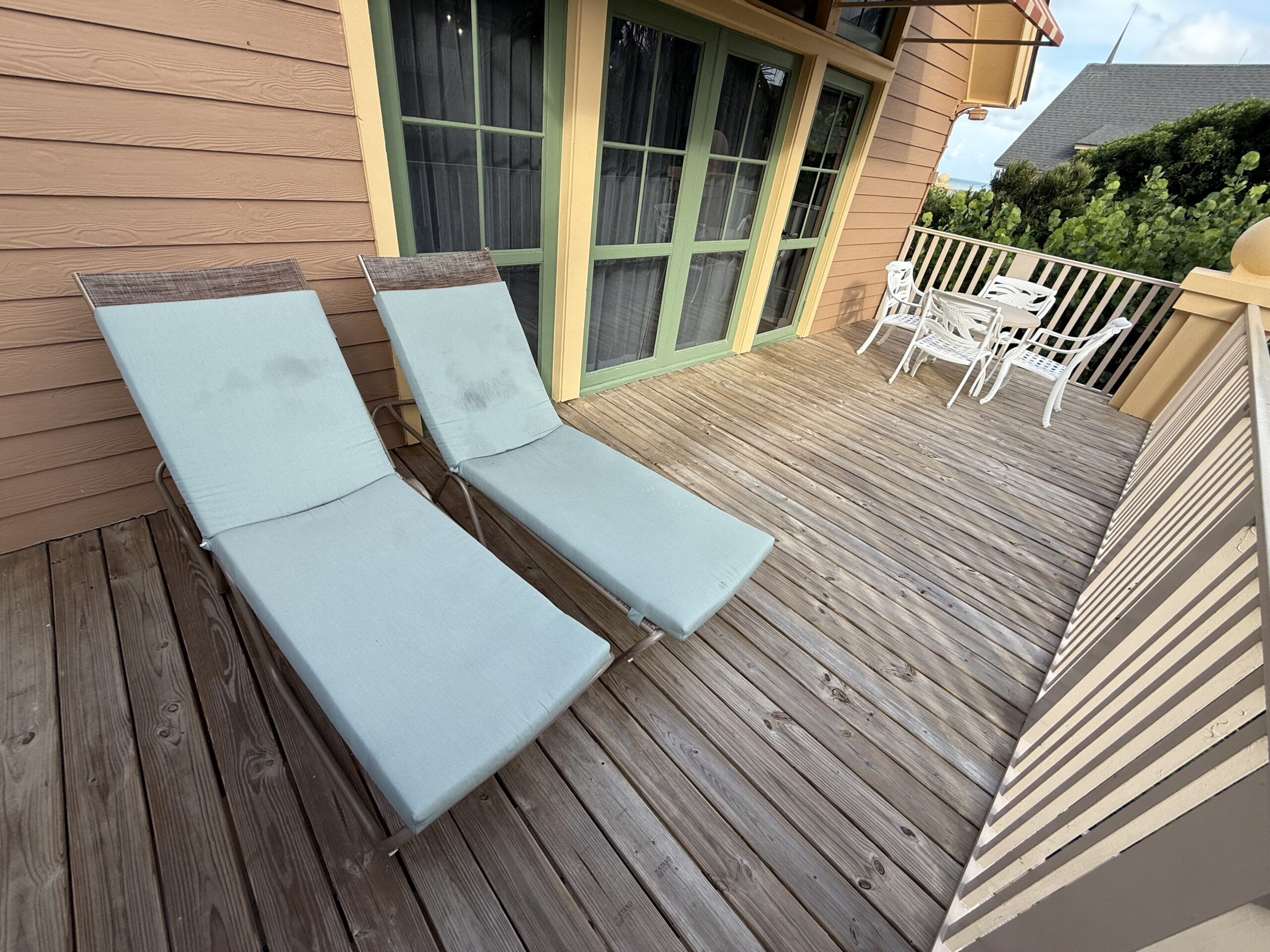 Blue lounge chairs and a white patio set on a Disney's Vero Beach Resort Cottage balcony—note, no Disney castle views here!
