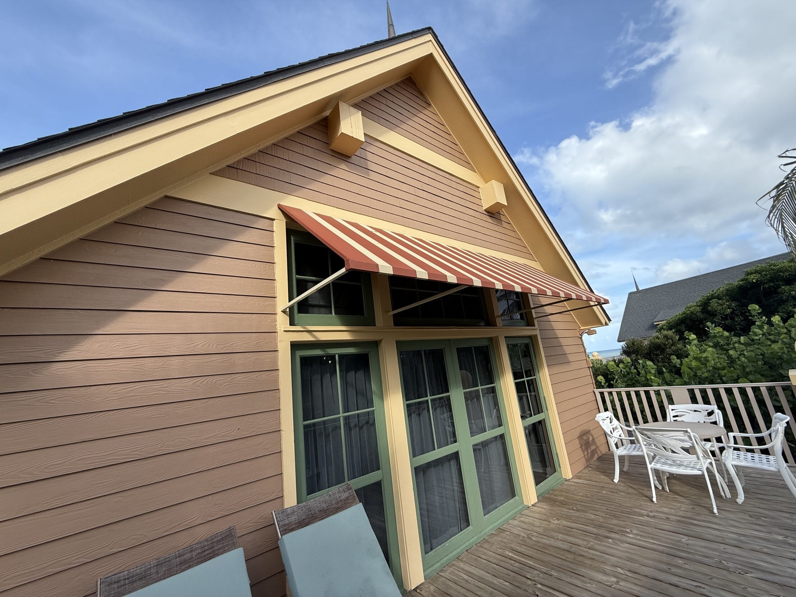 Charming cottage with striped awning and green windows, patio evokes Disney’s Vero Beach Resort, but no castle like Disneyland.