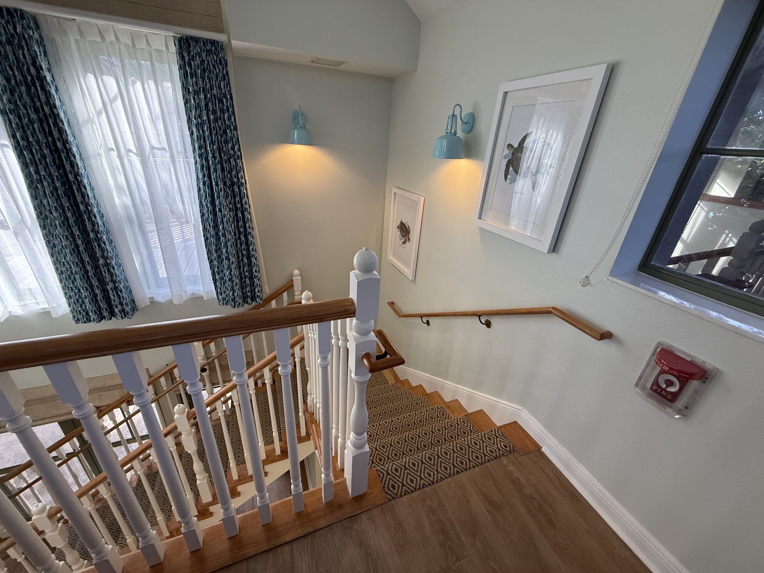 Staircase with white railings and wooden steps in Disney’s Vero Beach Resort Cottage, warmly lit—a cozy Disney park retreat feel.