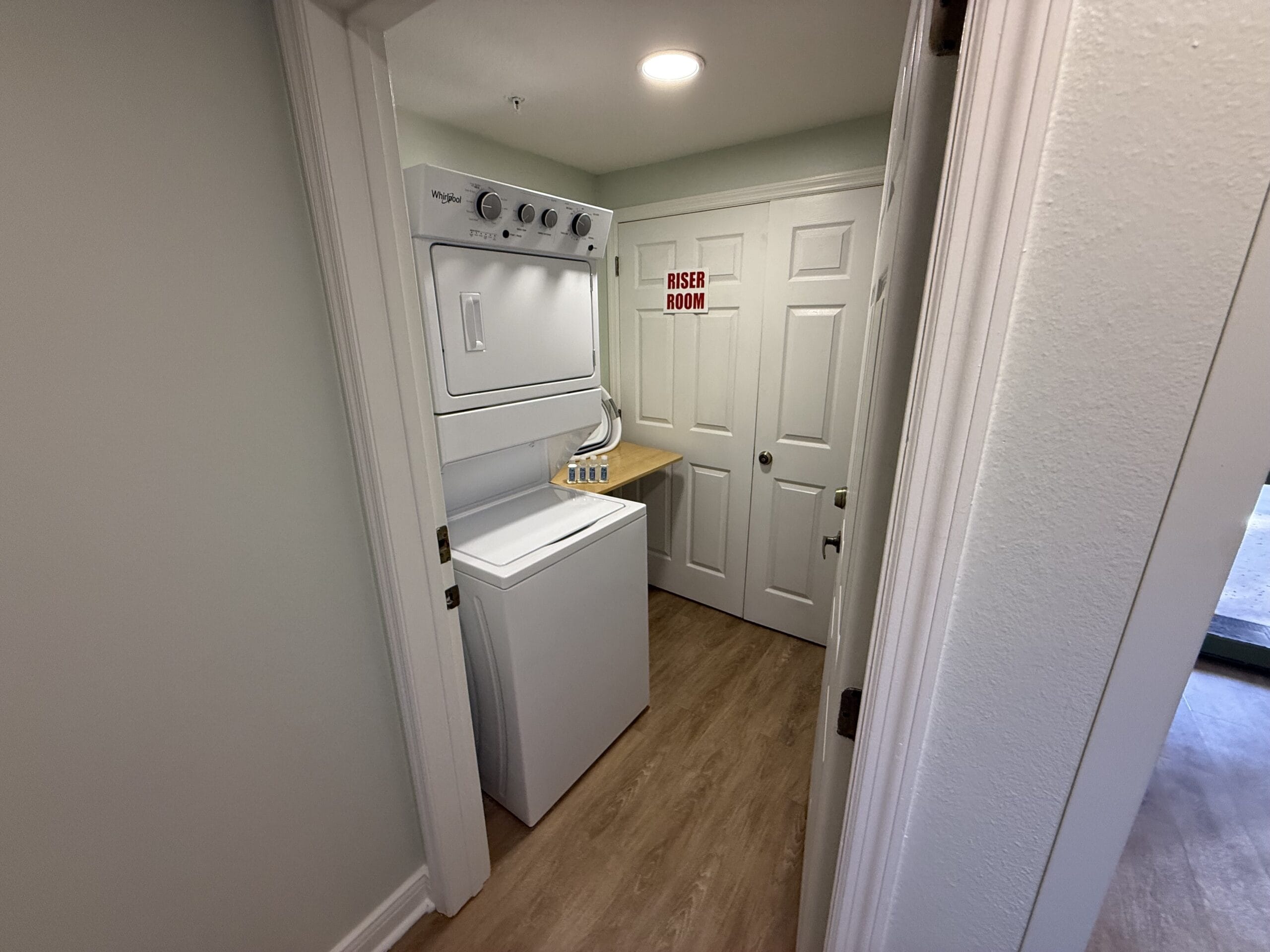 Compact washer and dryer stacked in Disney’s Vero Beach Resort laundry room, “Riser Room” sign visible, no castle present.