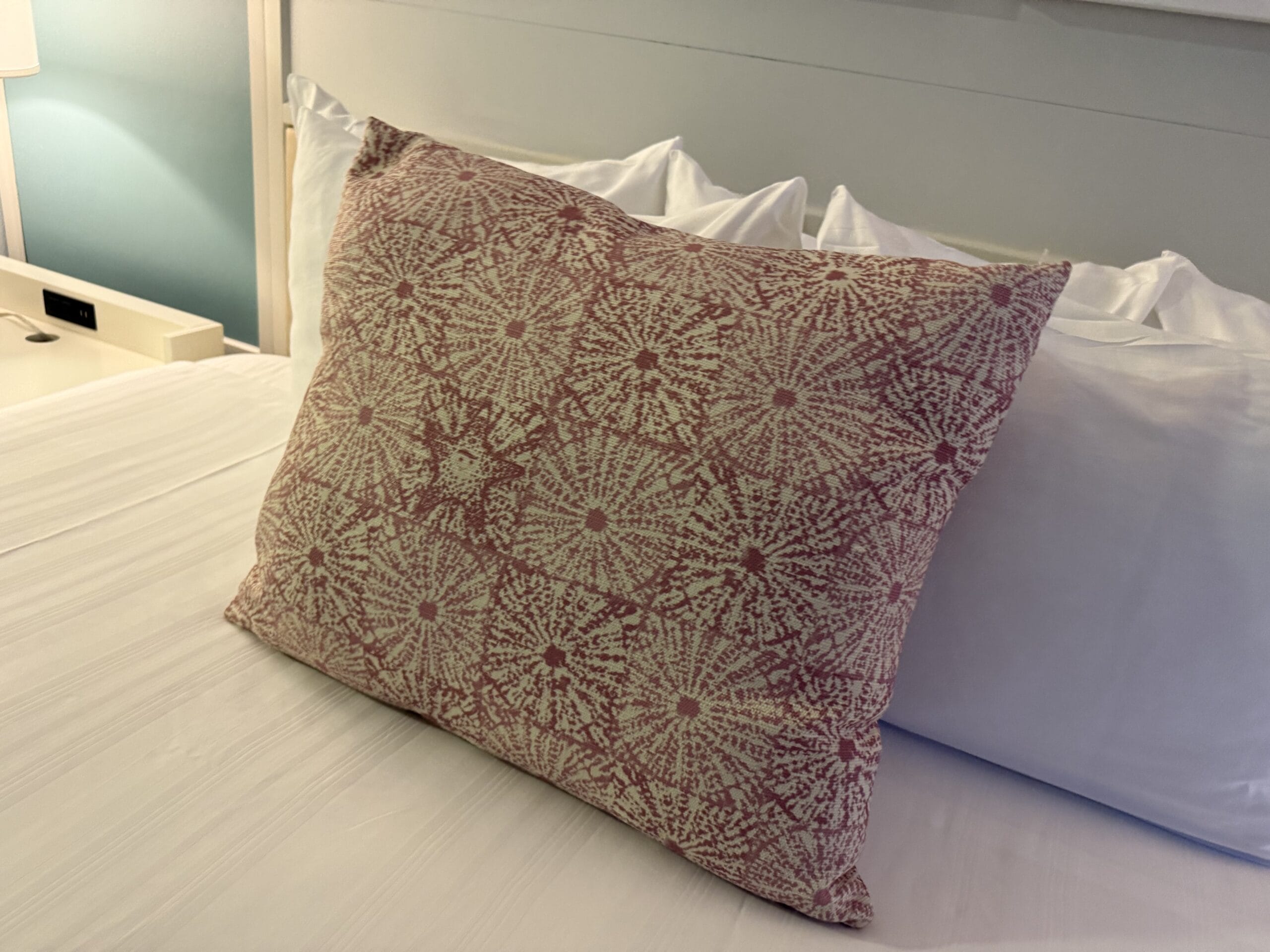 A pink and white patterned pillow on a tidy bed inside Disney’s Vero Beach Resort, capturing subtle Disney flair without castle views.
