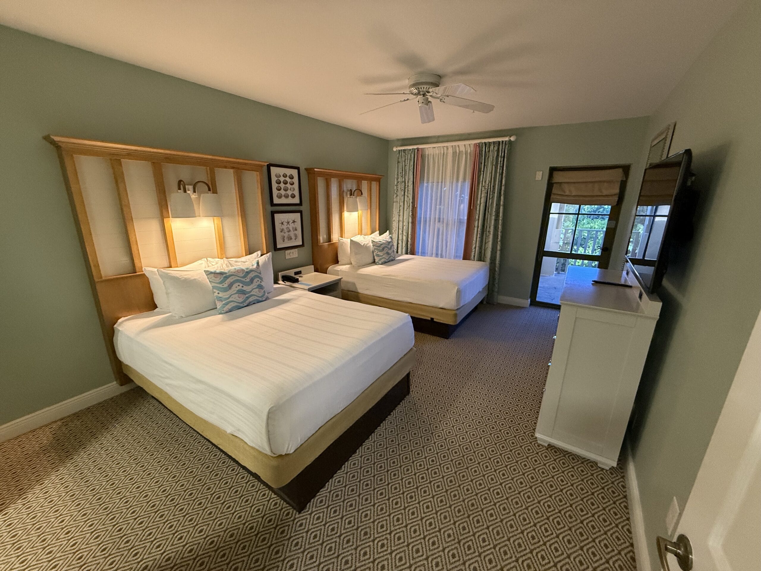 Disney's Vero Beach Resort hotel room with two double beds, TV, lamps, framed art, and a window—no castle like at Disney parks.