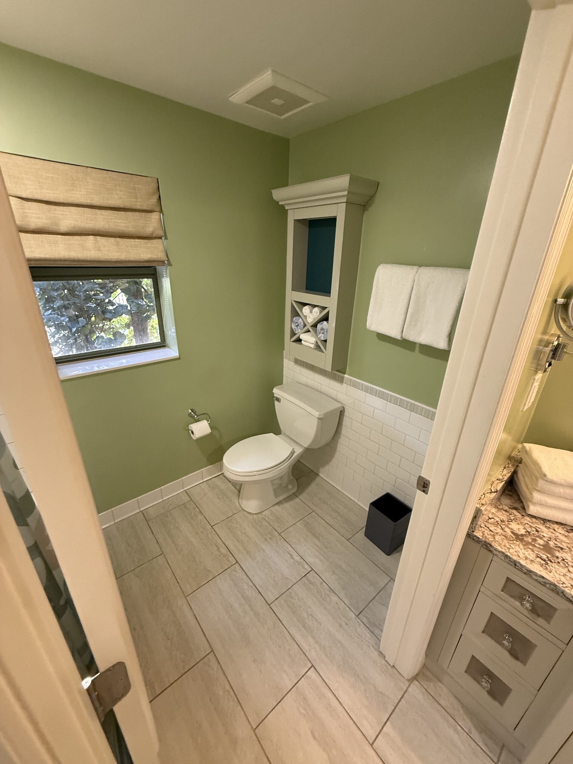 Small bathroom with green walls and granite vanity, echoing the cozy, fresh style of Disney’s Vero Beach Resort cottages.