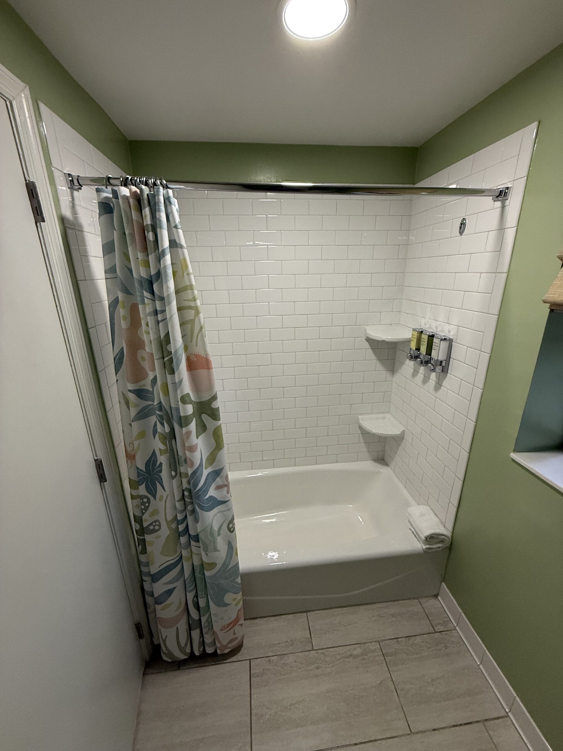Resort Cottage bath with white tile, vibrant shower curtain, and wall toiletries—just like Disney’s Vero Beach Resort, no castle here!