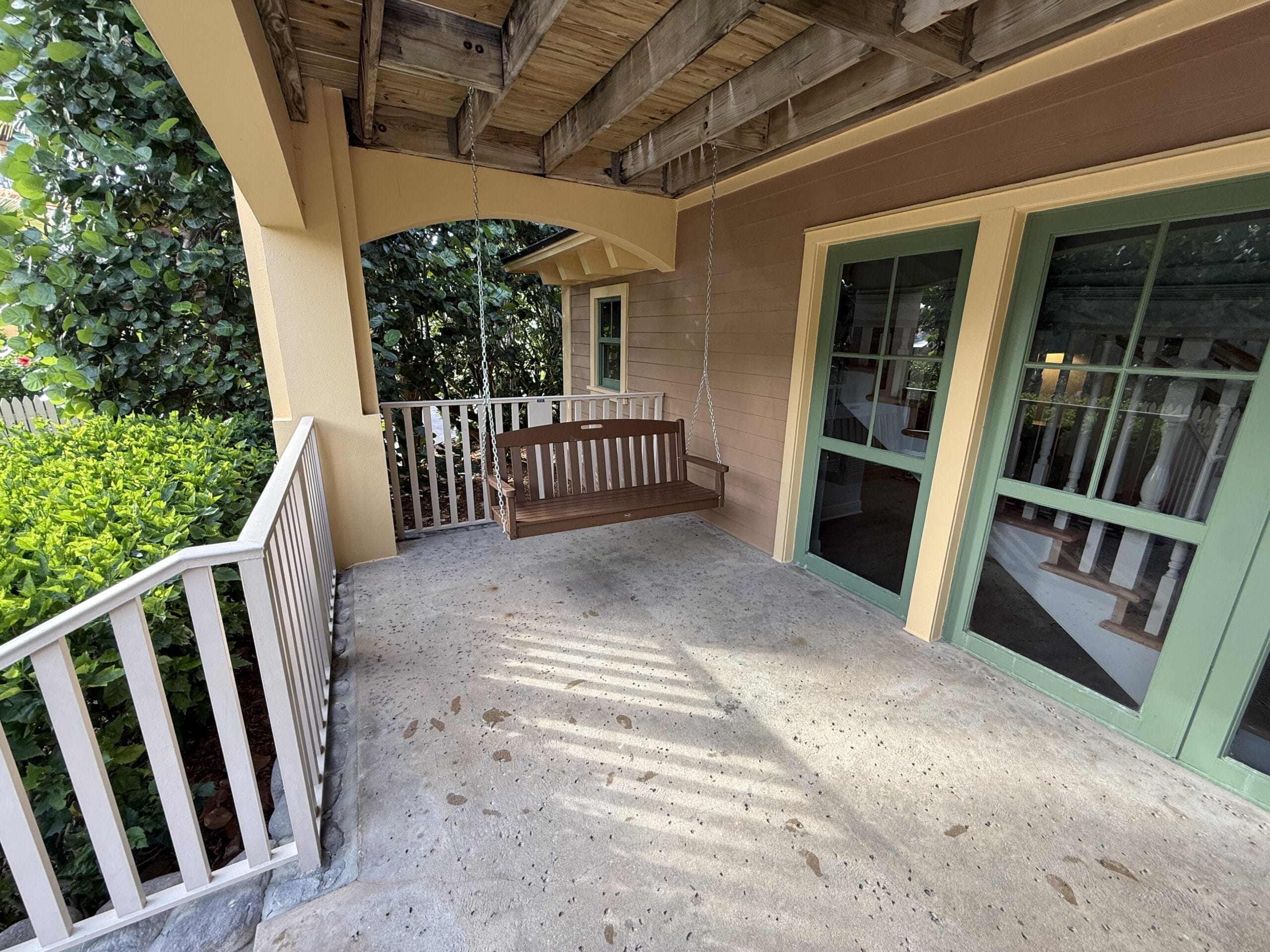 Wooden porch swing on a covered patio at a charming cottage near Disney’s Vero Beach Resort, not far from Disney castle parks.