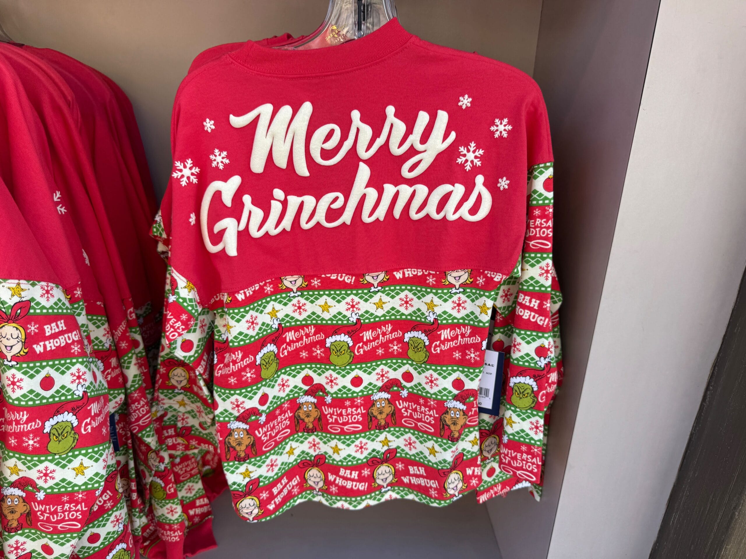 Festive red and green "Merry Grinchmas" sweater with Grinch designs on display at Universal Orlando, not to be confused with Disney parks.