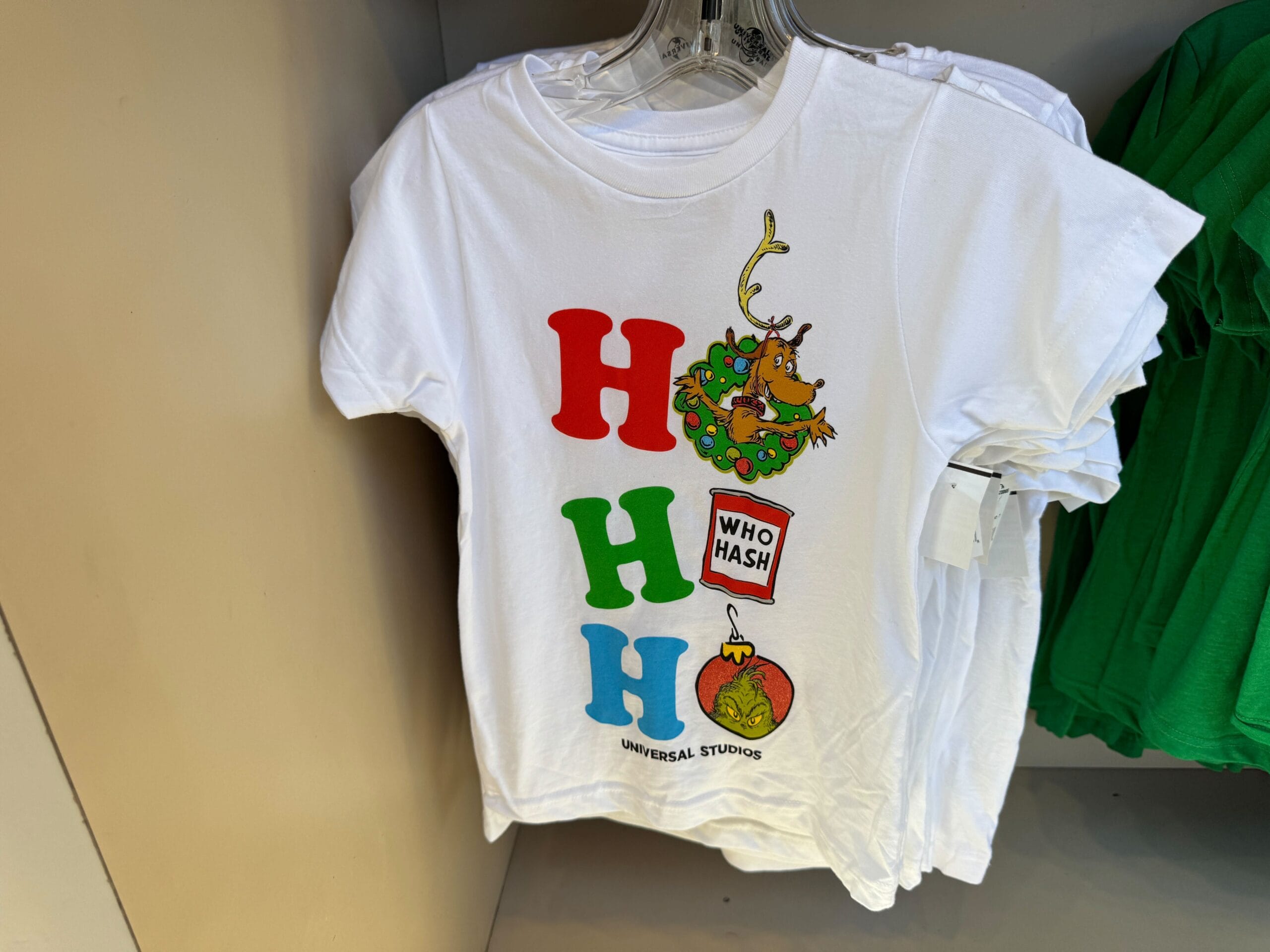 White Grinchmas tee with “H H H” in festive colors, Universal Orlando merch—no Disney castle here like at Cinderella or Sleeping Beauty's.
