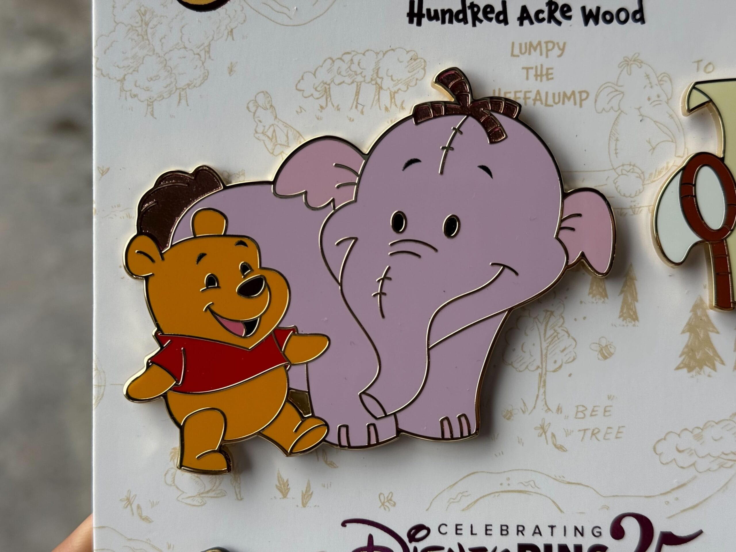 A Disney pin of Winnie the Pooh smiling and walking beside Lumpy the Heffalump.