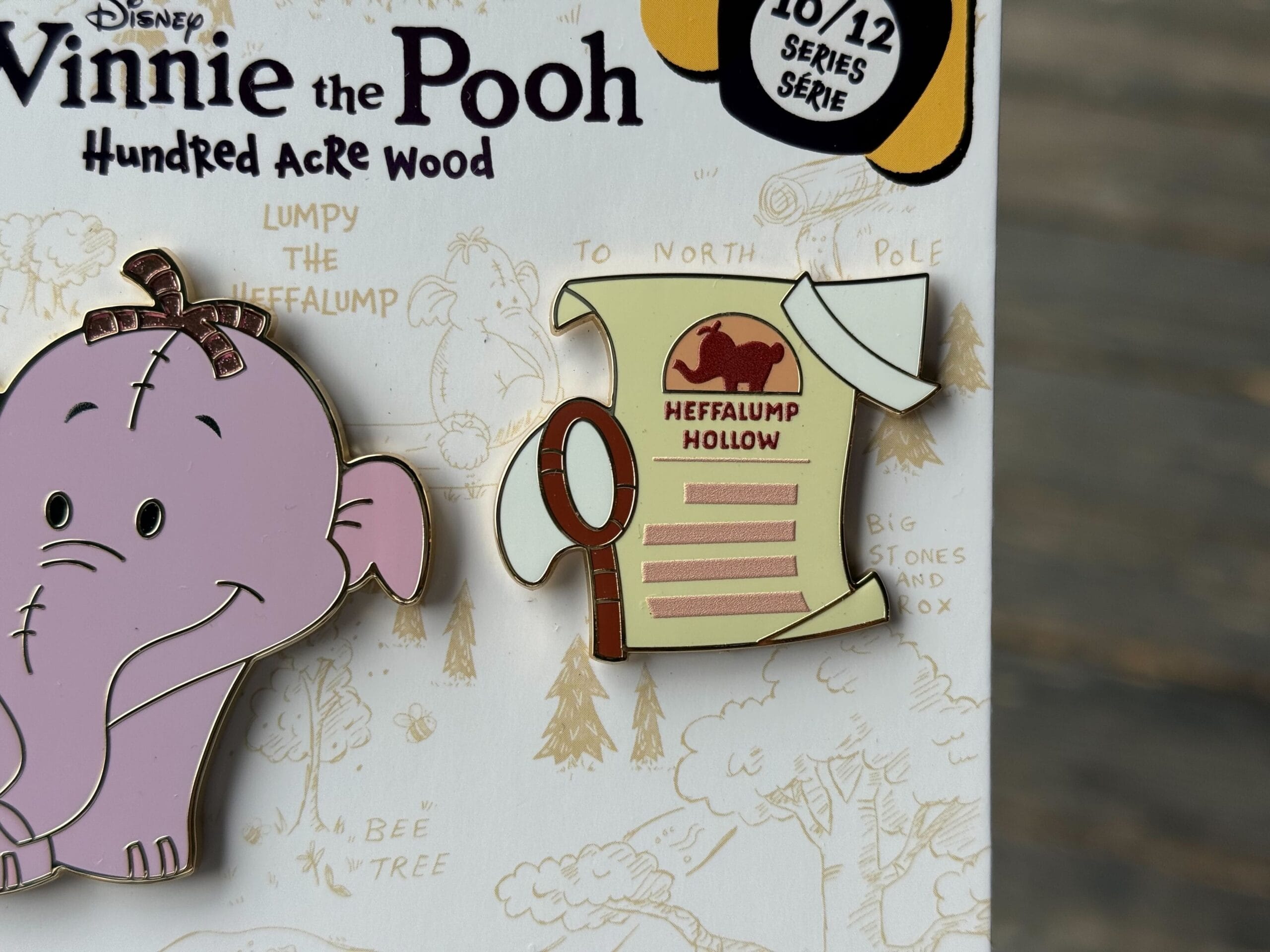 A Heffalump pin and a map pin labeled “Heffalump Hollow” on a Winnie the Pooh-themed background.