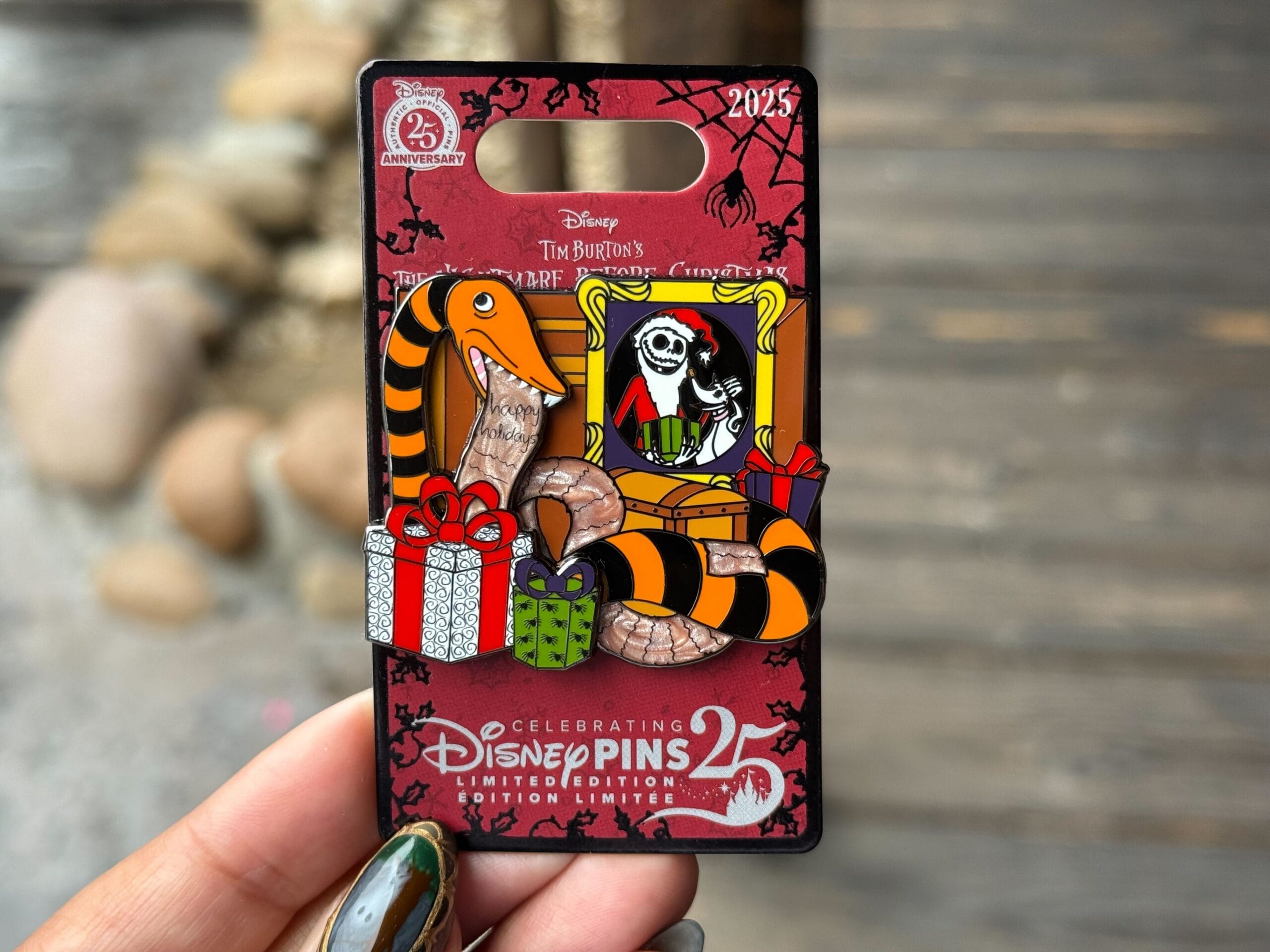 A Nightmare Before Christmas pin featuring the orange and black giant snake eating a "Happy Holidays" list, surrounded by presents and a Jack Skellington portrait.
