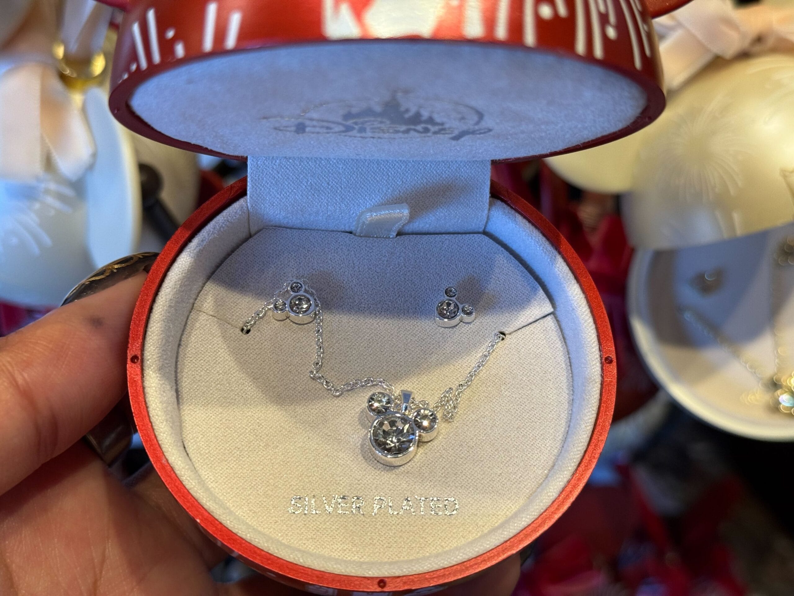 A silver Mickey Mouse necklace in a round red box, festive Disney Parks holiday merchandise for Christmas 2025.