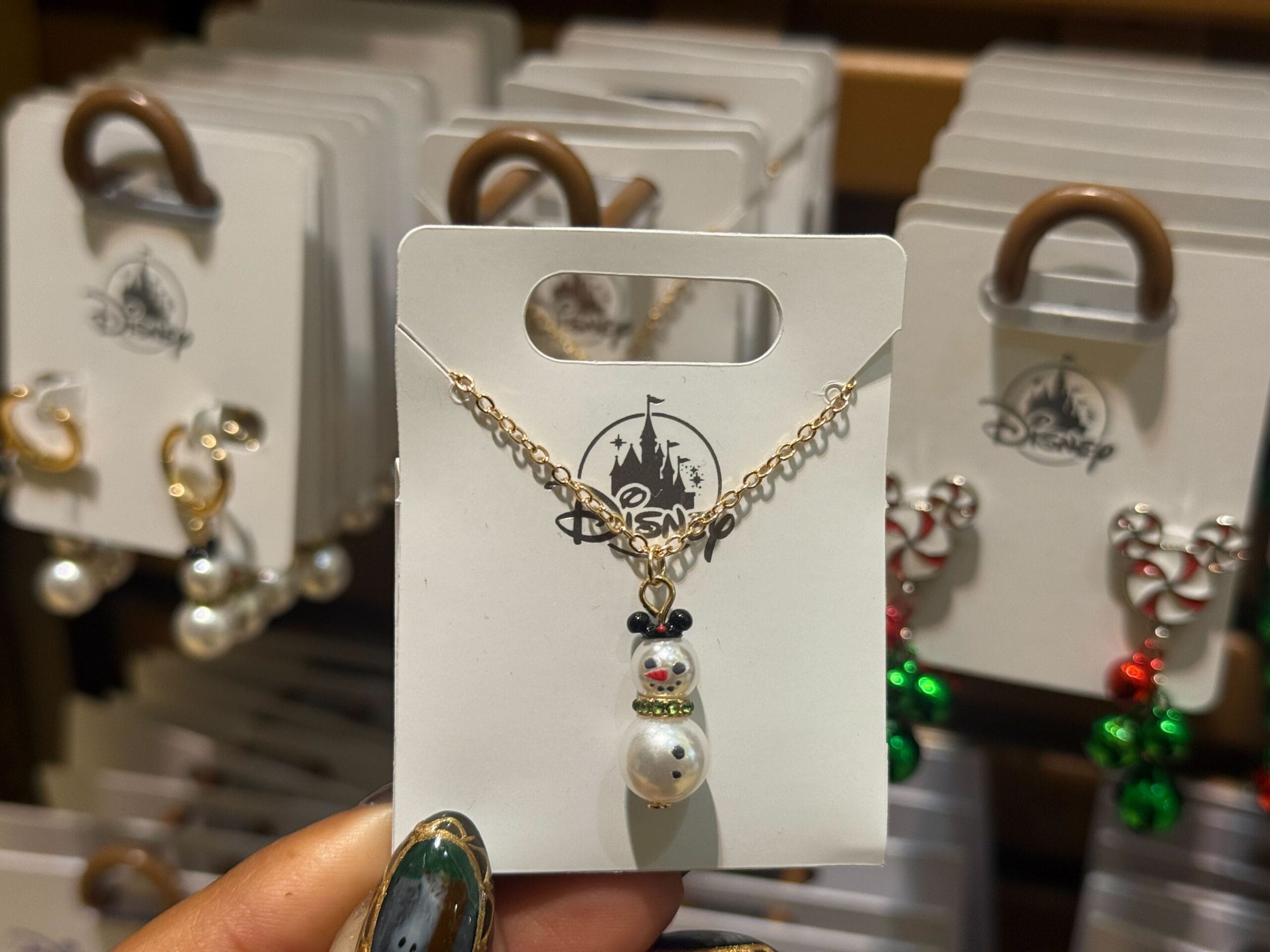 A snowman pendant necklace showcased on a 2025 Disneyland Christmas card featuring festive jewelry, exclusive to Disney Parks.