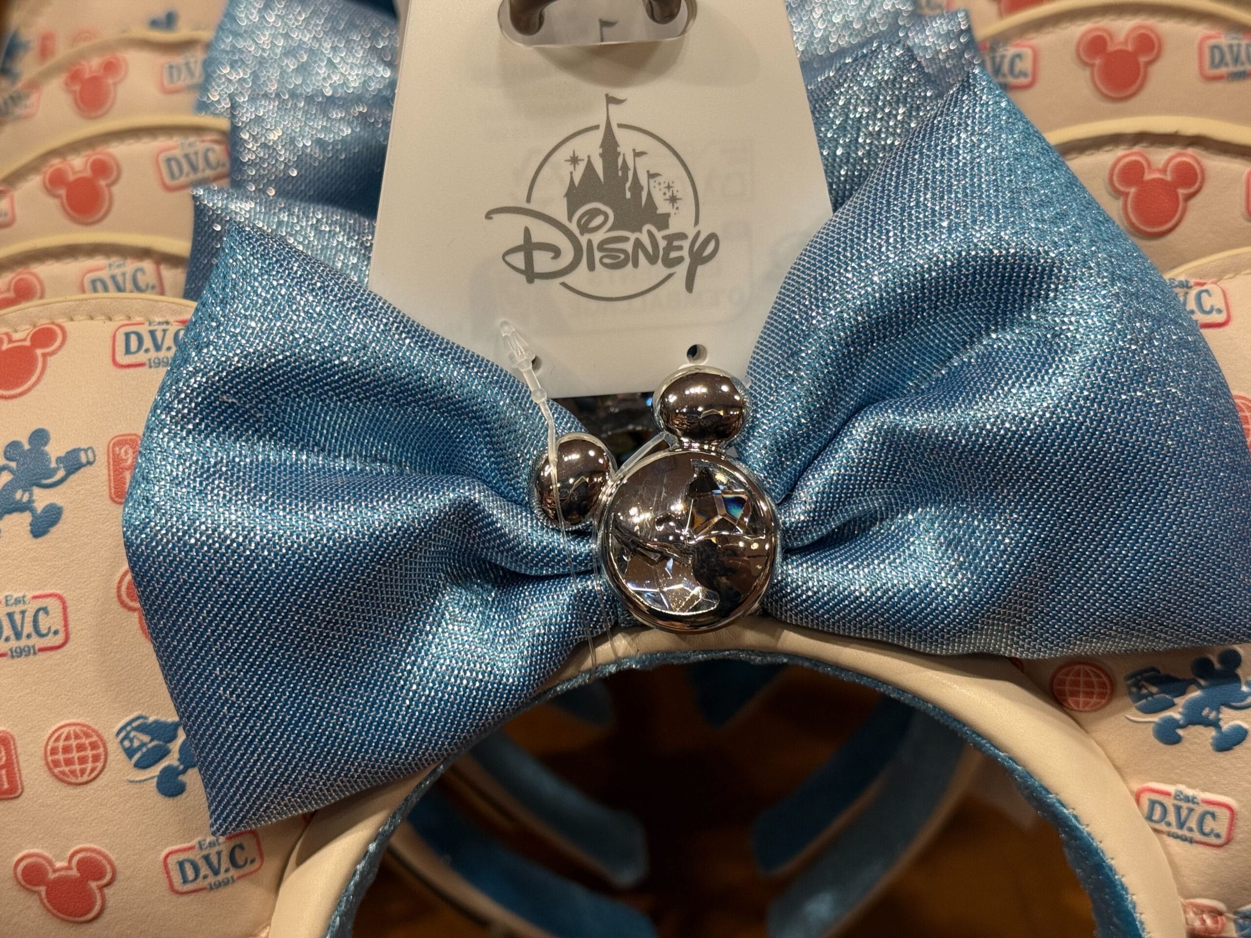 Close-up of Disneyland blue bow headband with silver Mickey ears and DVC Member pattern, red Mickey icons evoking park magic.
