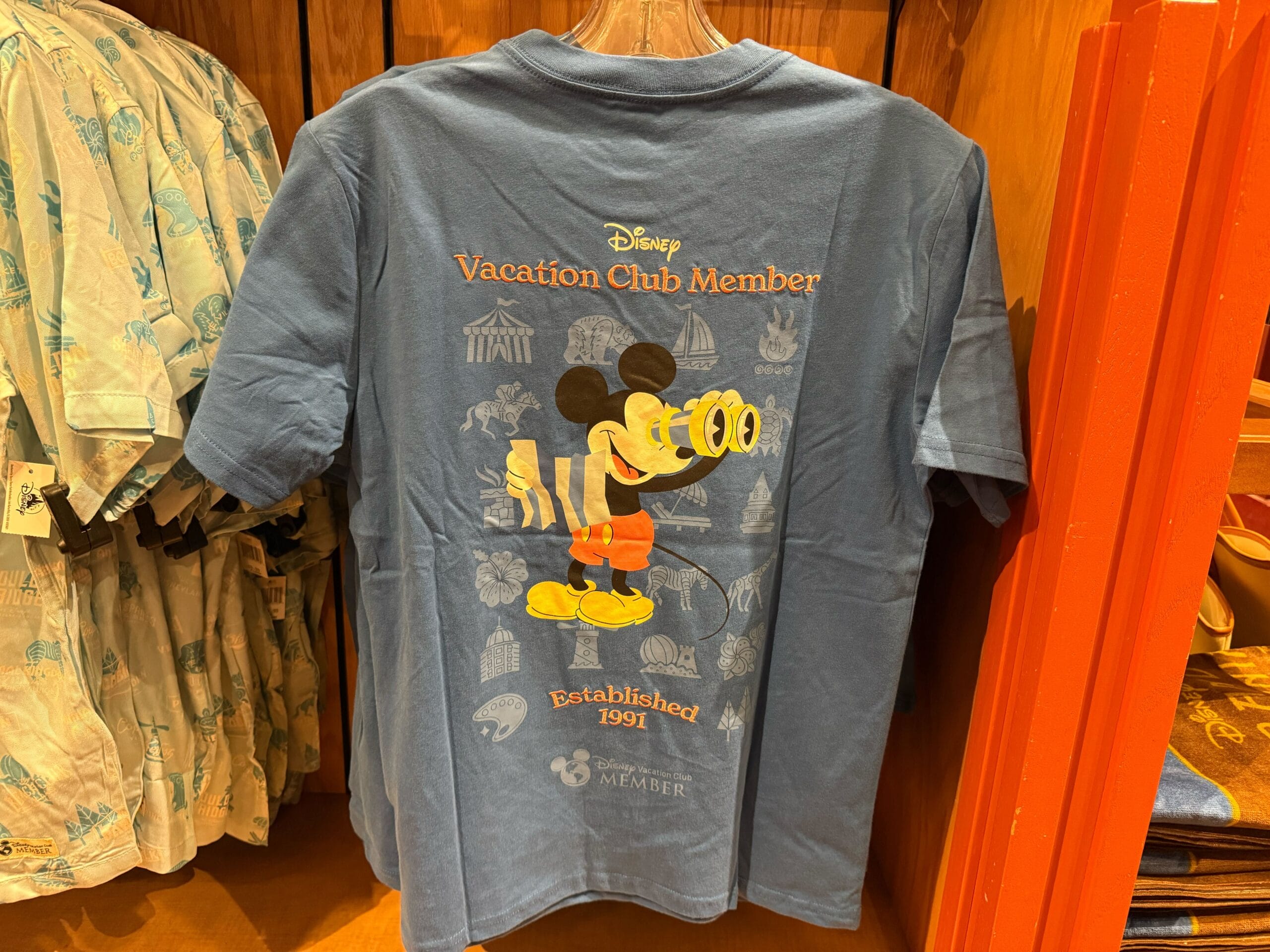 Blue Disneyland shirt shows Mickey Mouse with binoculars, a great DVC Member item—no castle, but classic Disney Park vibes.
