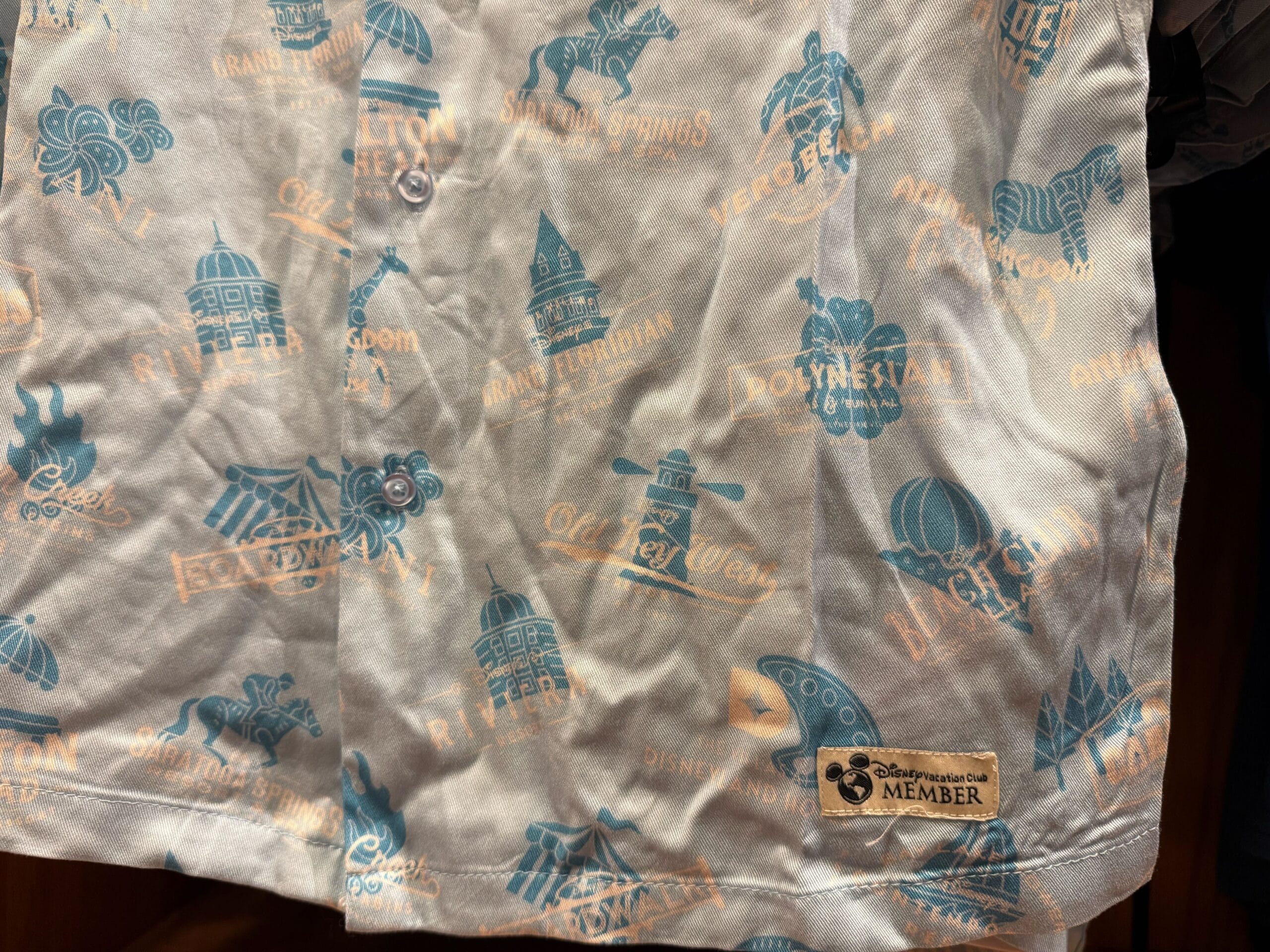 Shirt with blue and tan Disney Resort icons, "Disney Vacation Club Member" patch, and classic Mickey style, evoking park nostalgia.