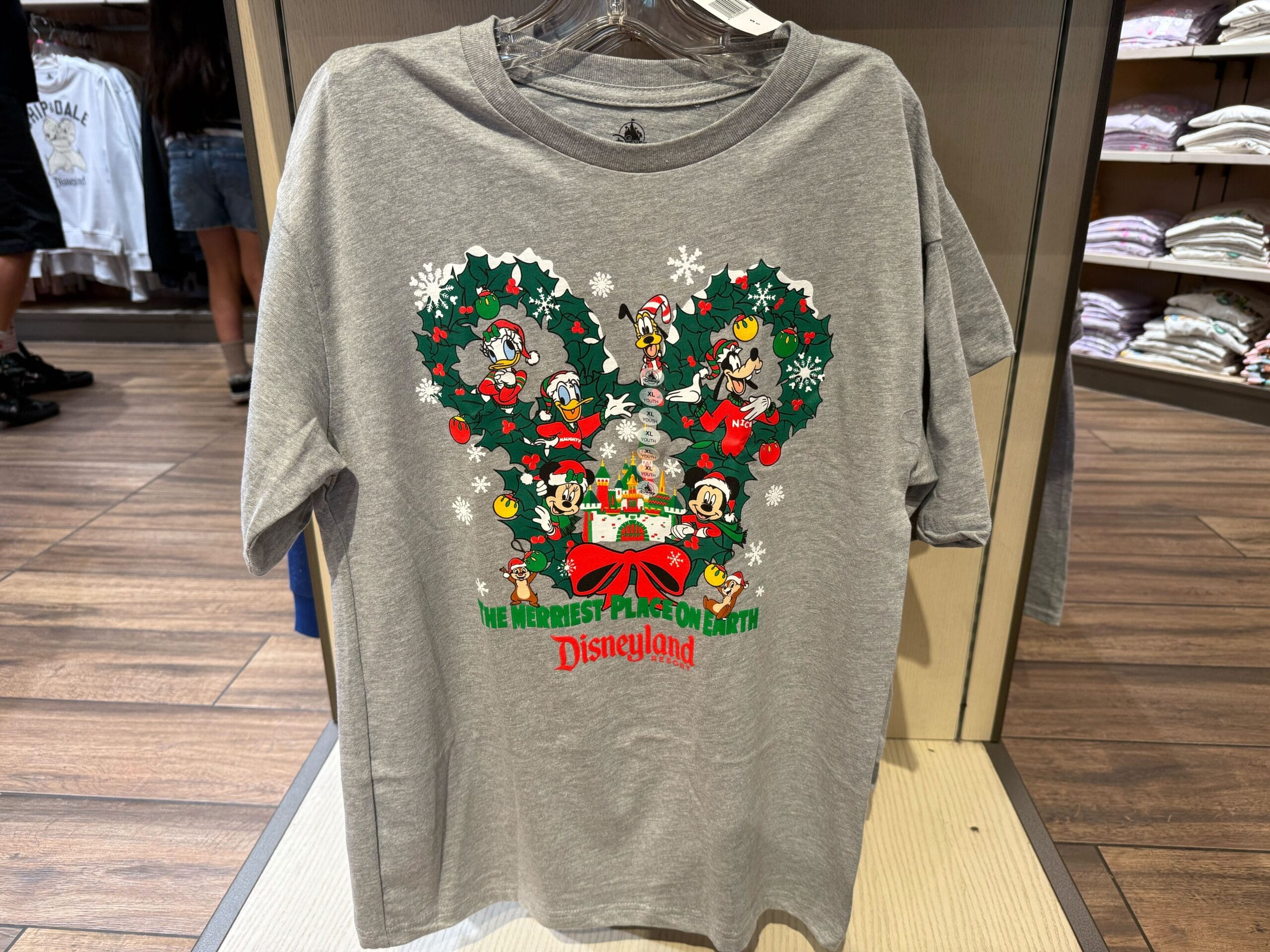 Gray Disneyland holiday shirt features Mickey & friends in a wreath; festive 2025 style, inspired by Disney Parks worldwide.