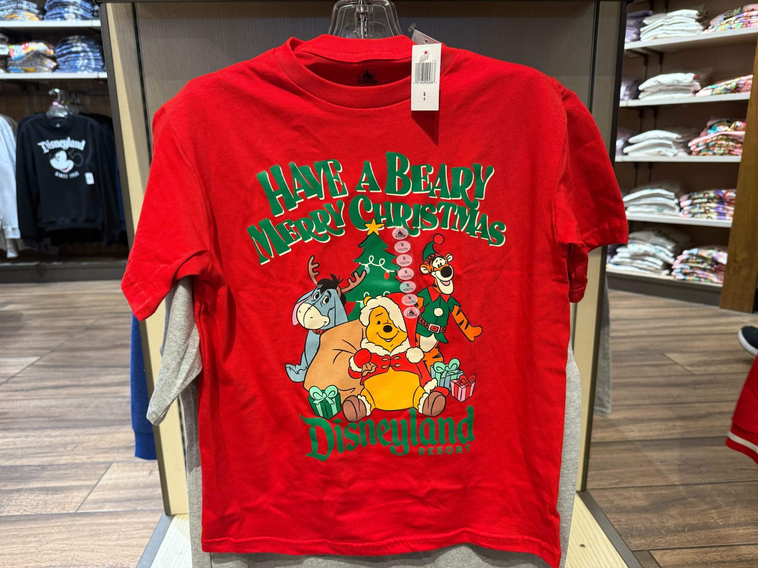 A red shirt featuring a cartoon, part of 2025 Disneyland holiday merchandise, exclusive to Disney Parks and reminiscent of Main Street.