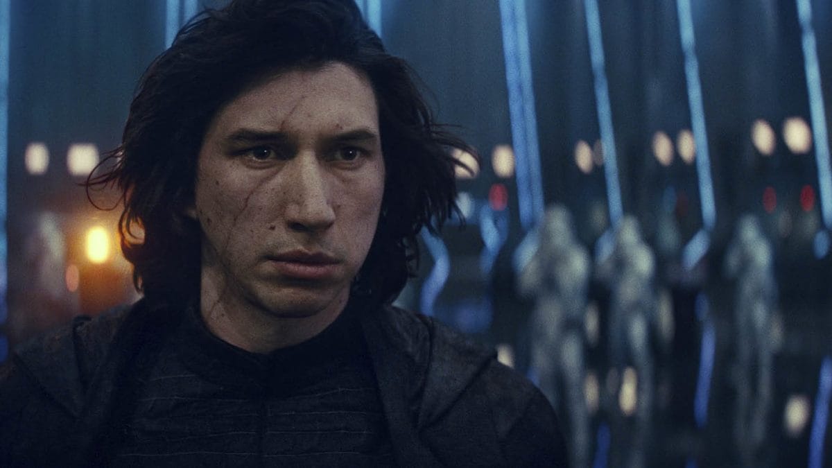 A man with long dark hair and a scarred face stands before armored figures in a dim, futuristic scene reminiscent of Star Wars: Galaxy's Edge at Disney Parks.
