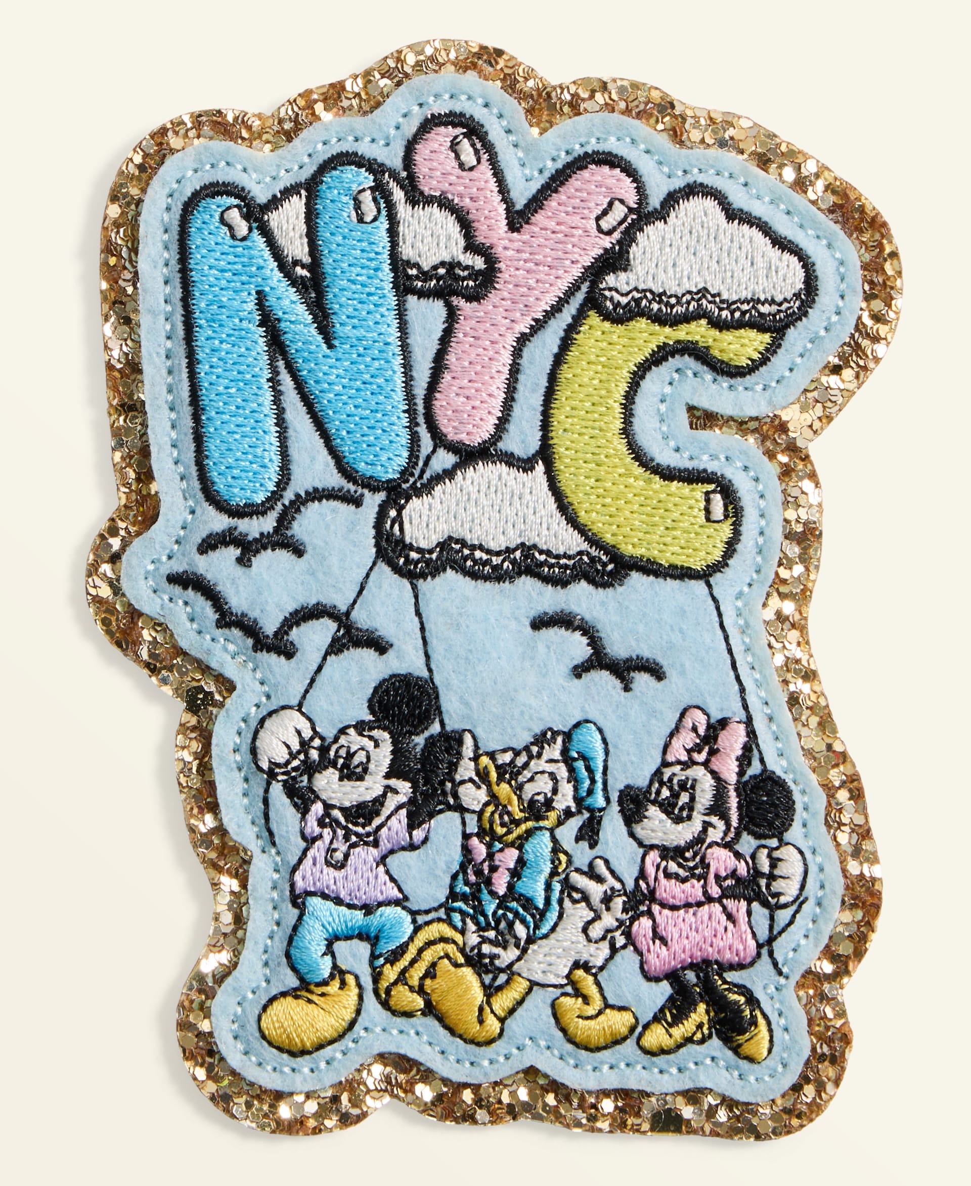 Disney’s Holiday patch at Macy’s shows Mickey, Minnie, and Donald with “NYC” balloon letters; no castle like those at the Disney parks.