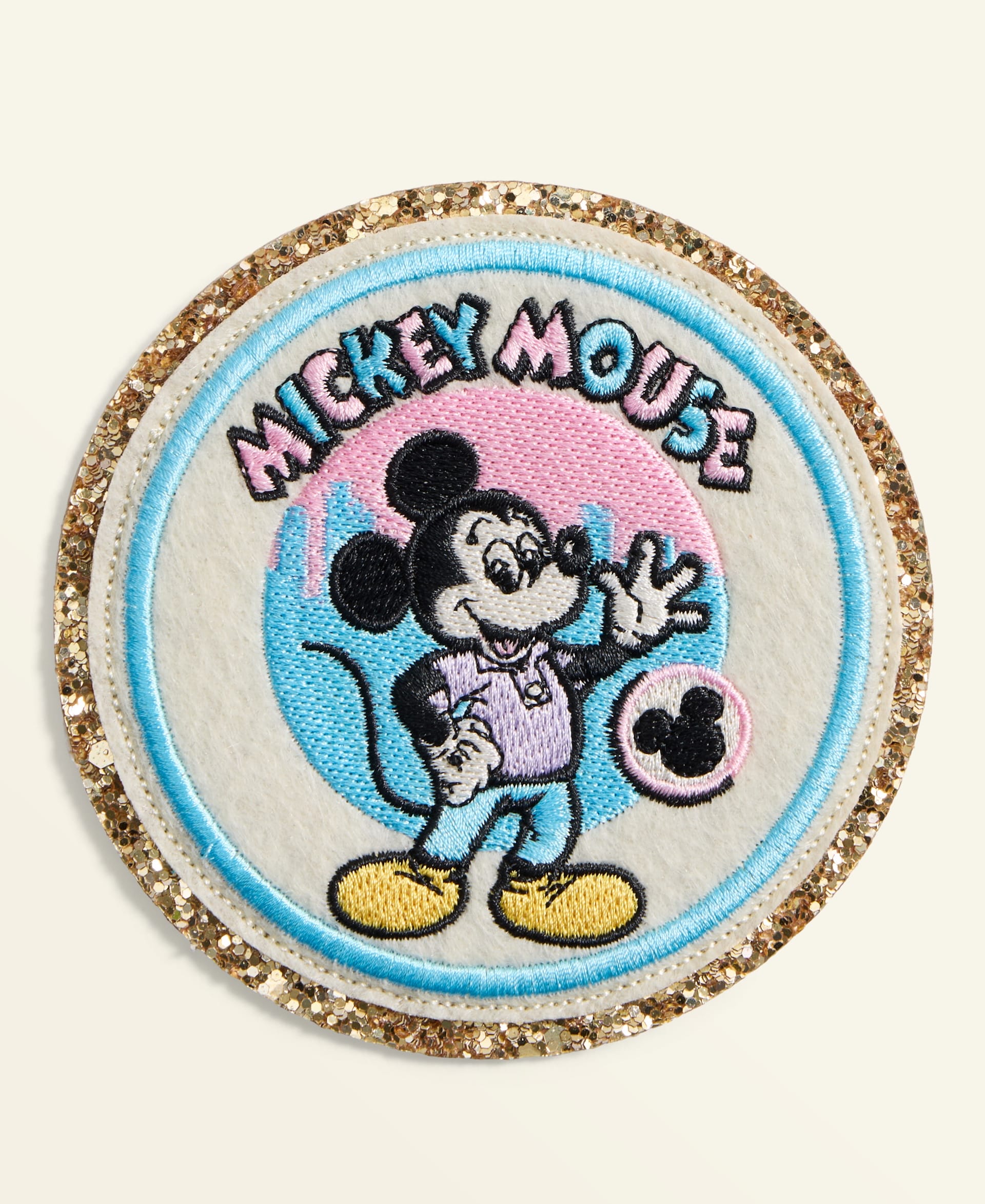 Circular Disney patch featuring Mickey Mouse and "Mickey Mouse" text, gold glitter trim—part of a holiday park collection.