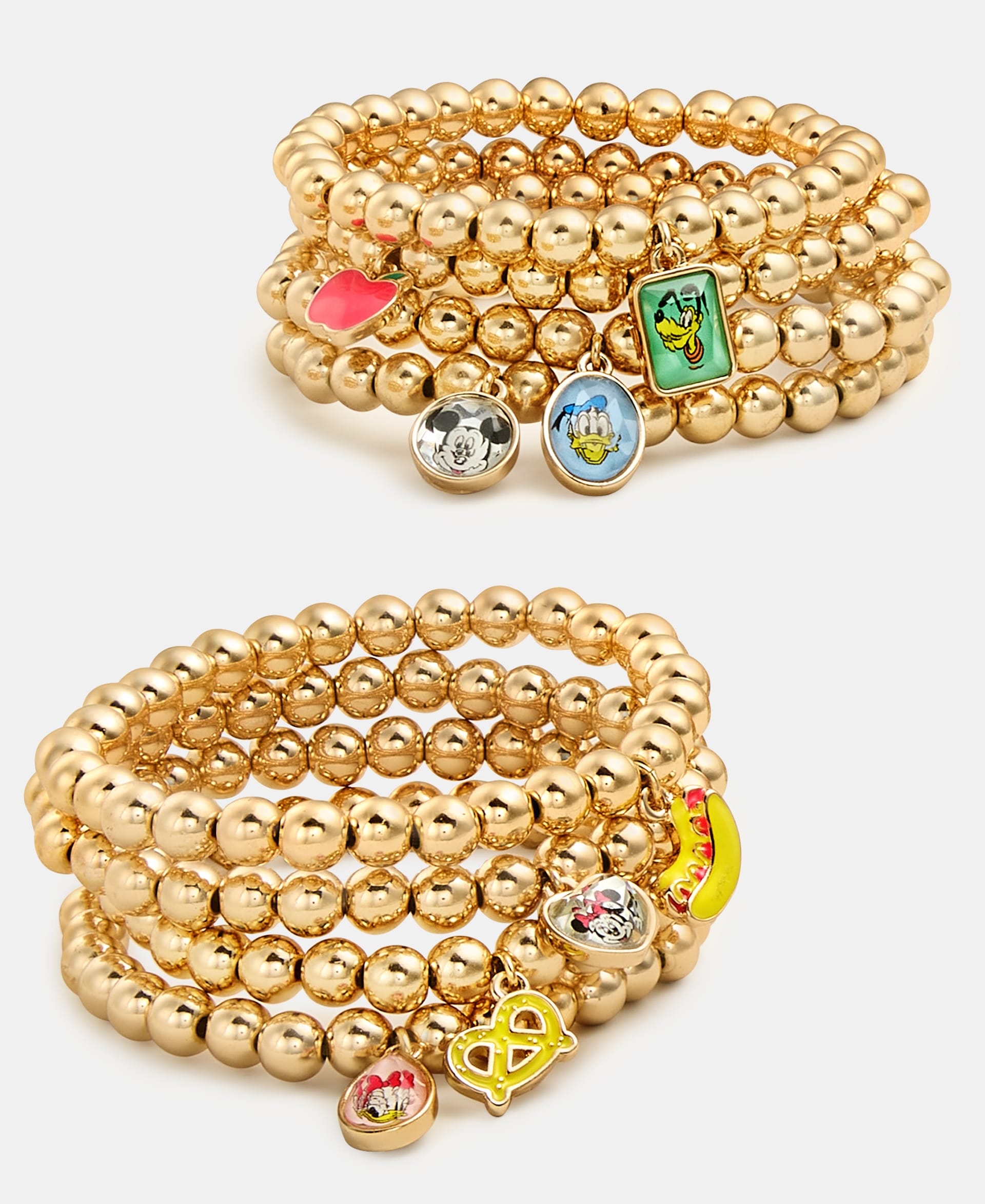 Two stacks of gold beaded bracelets with Disney 2025 Holiday Collection charms, styled for Disney Parks, on a white background.