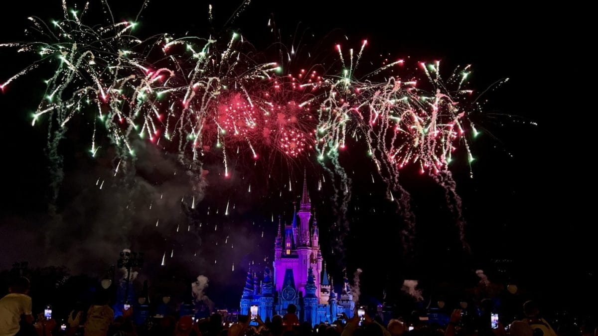 Vivid fireworks light up Magic Kingdom’s Cinderella Castle, instantly recognizable by its blue turrets, as crowds watch below.