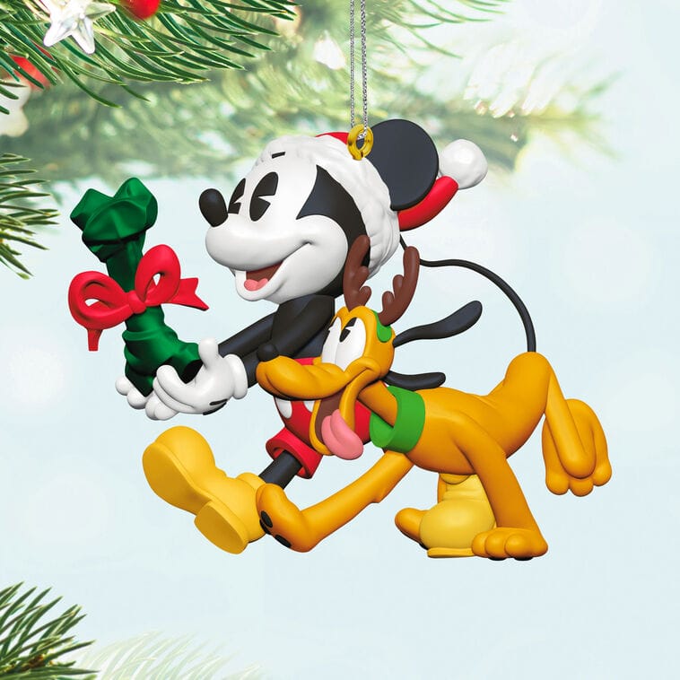 Mickey Mouse in a Santa hat runs with Pluto near a Christmas tree, like scenes at Disney parks—part of Hallmark’s ornament releases.