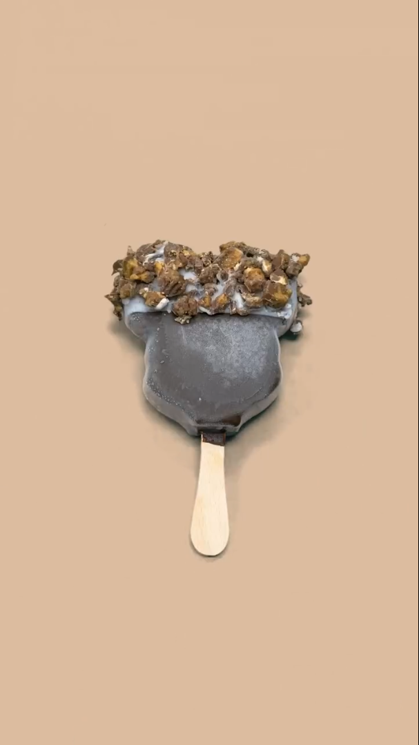 A Mickey's Premium Ice Cream bar with the top half dipped in white chocolate with crushed Butterfinger candy.