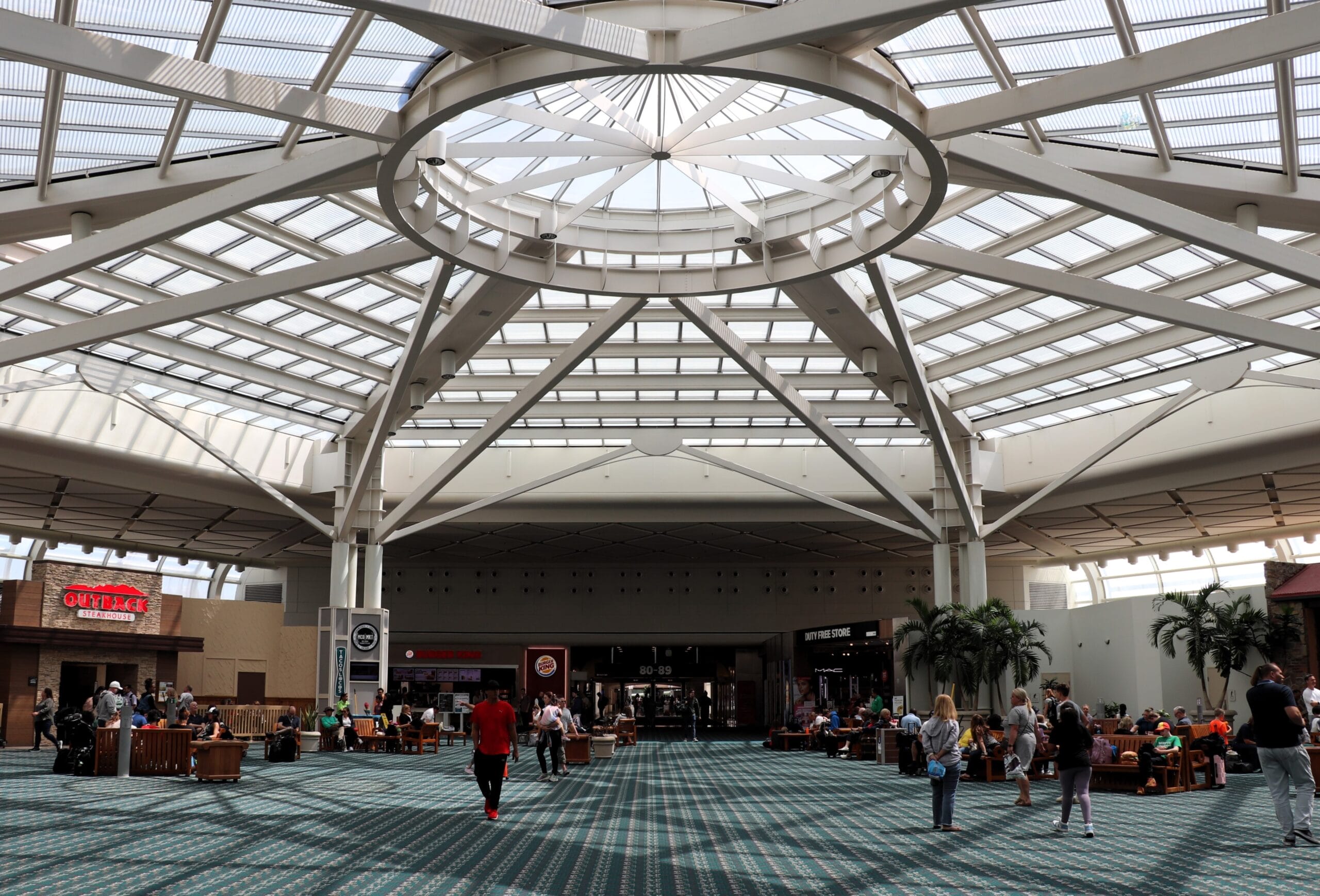 Travelers sitting and walking in the bright, updated terminal at Orlando International Airport, a gateway to Walt Disney World.