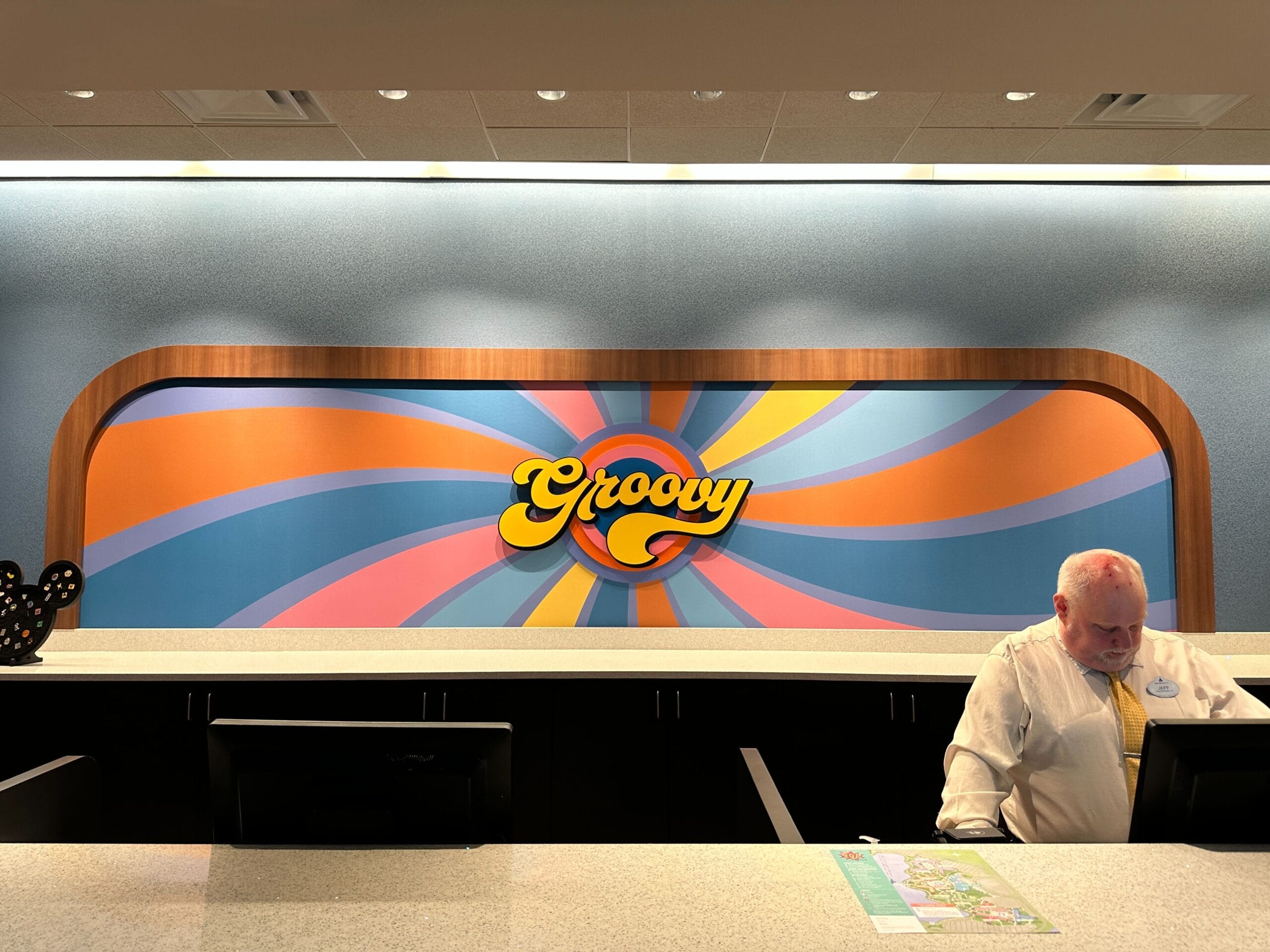 Bright "Groovy" sign with a swirled pink, blue, yellow, and orange design pops behind Disney's Pop Century Resort check-in.