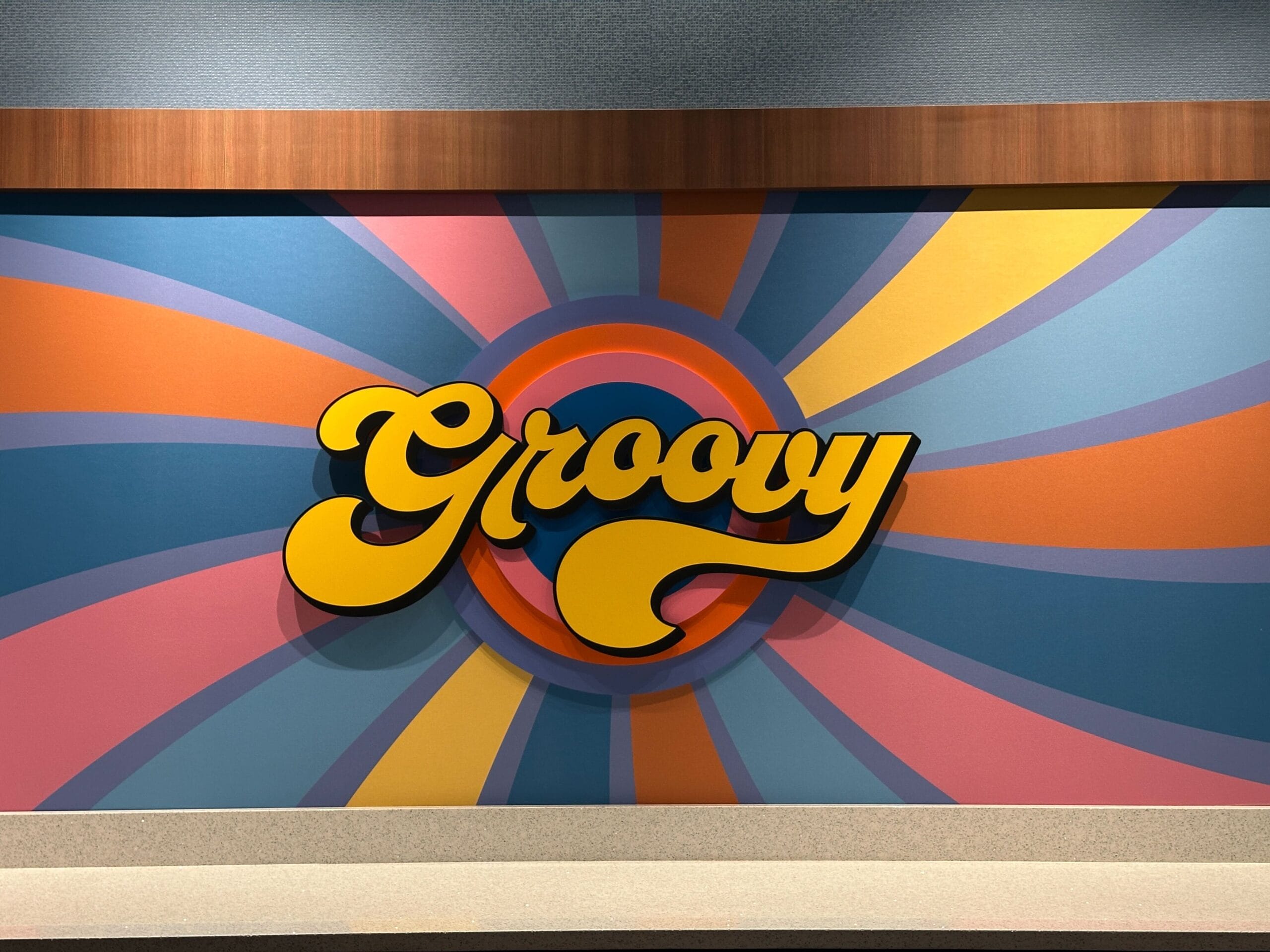 Bright "Groovy" sign with a swirled pink, blue, yellow, and orange design pops behind Disney's Pop Century Resort check-in.