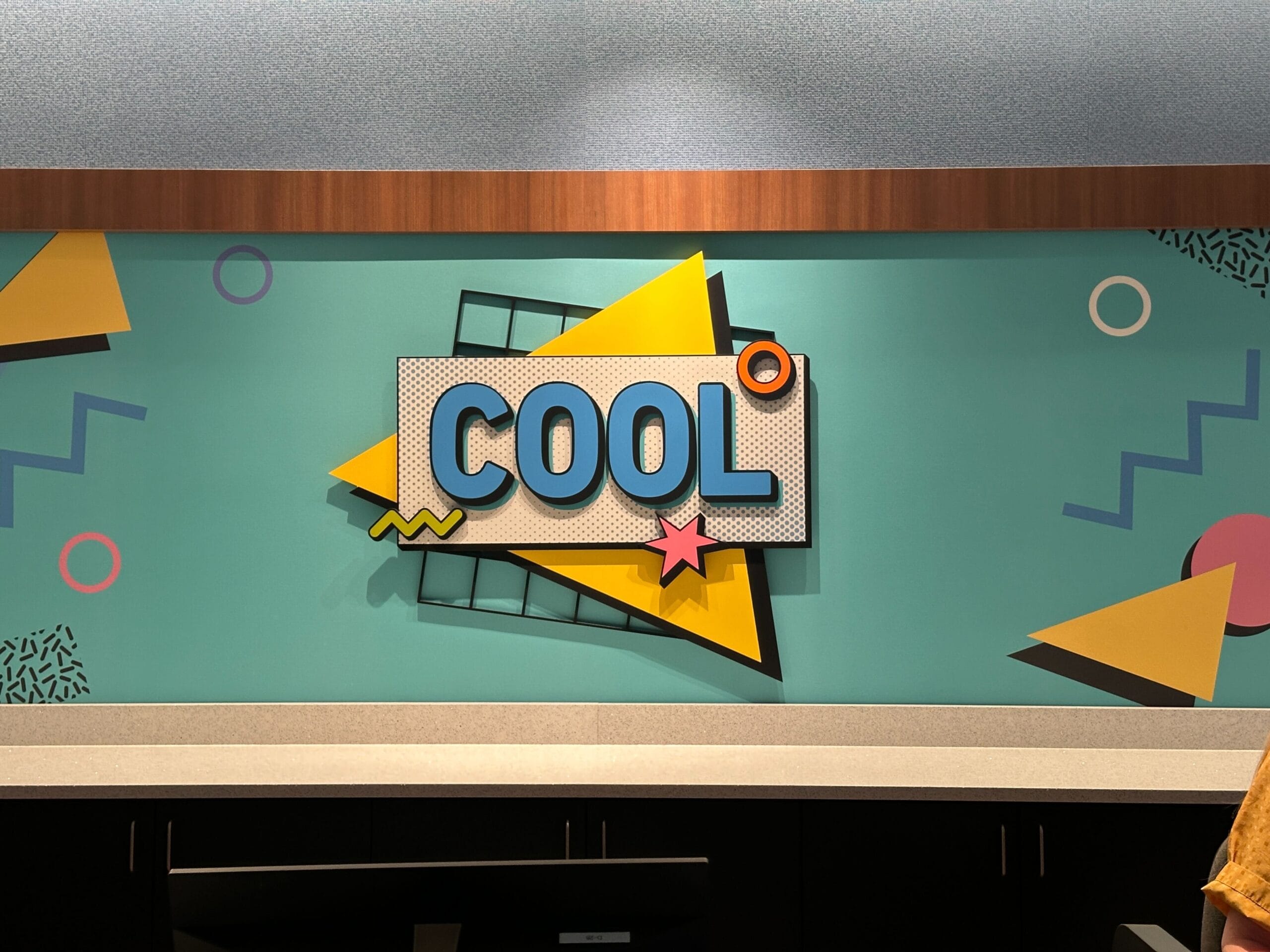 A vibrant wall of bold geometric shapes says "COOL" near the check-in area at Disney’s Pop Century Resort.