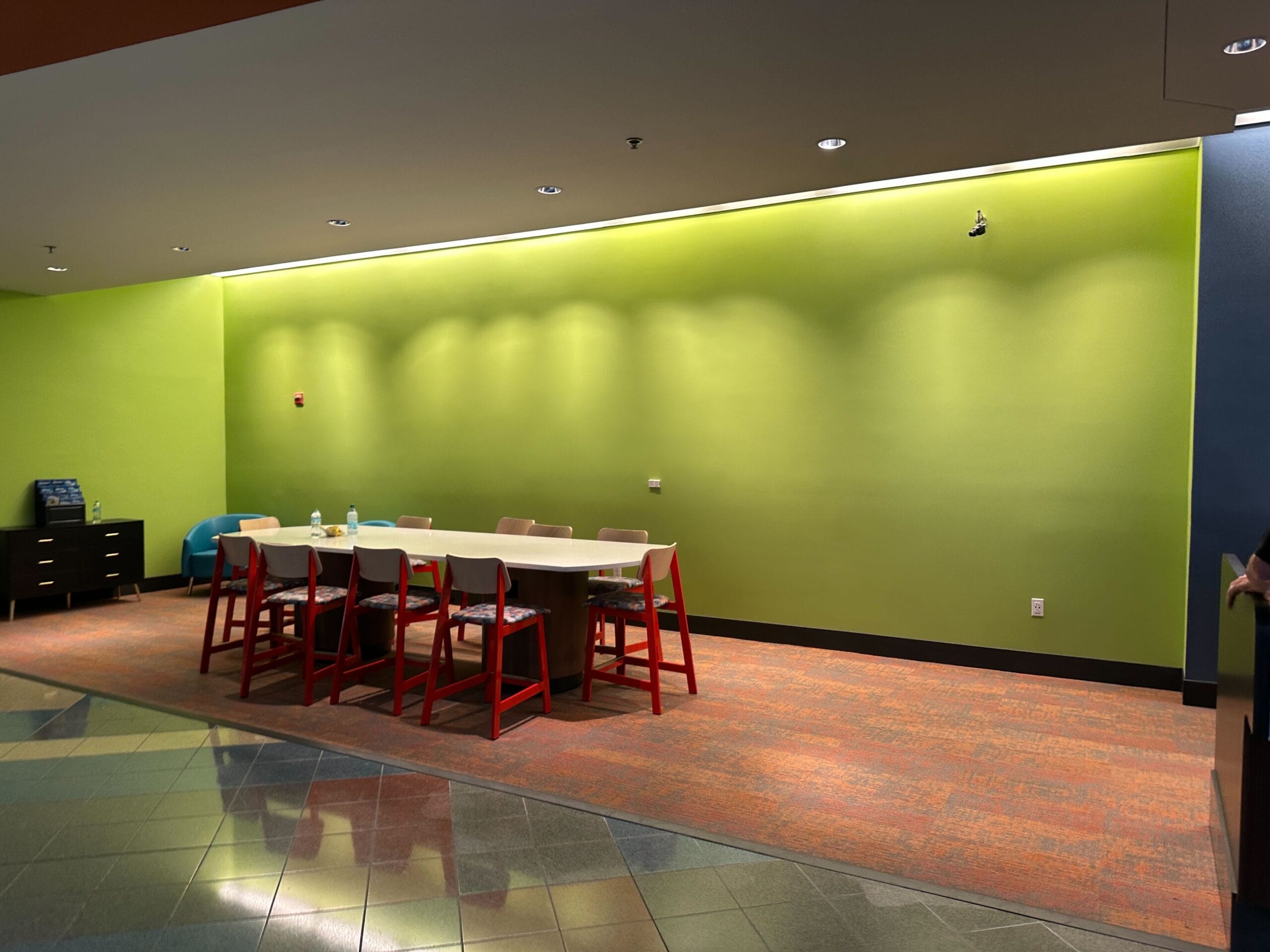 A meeting table with red chairs against a green wall in the lobby at Disney's Pop Century Resort.