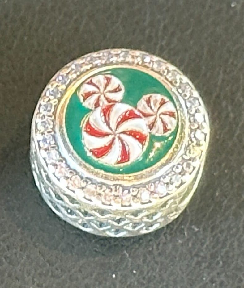 Round silver Holiday Pandora Charm featuring a peppermint Mickey Mouse head on a green background.
