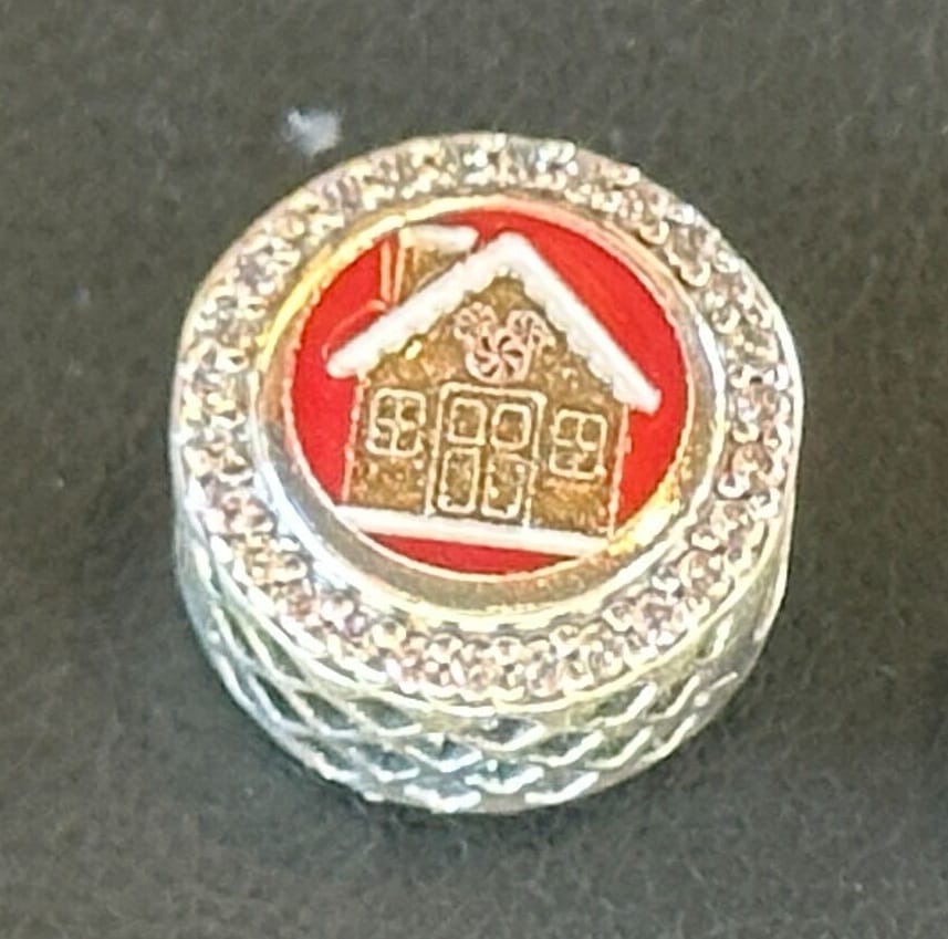Round silver Holiday Pandora Charm with a red center, featuring a gold gingerbread house with a peppermint Mickey head and white icing details.