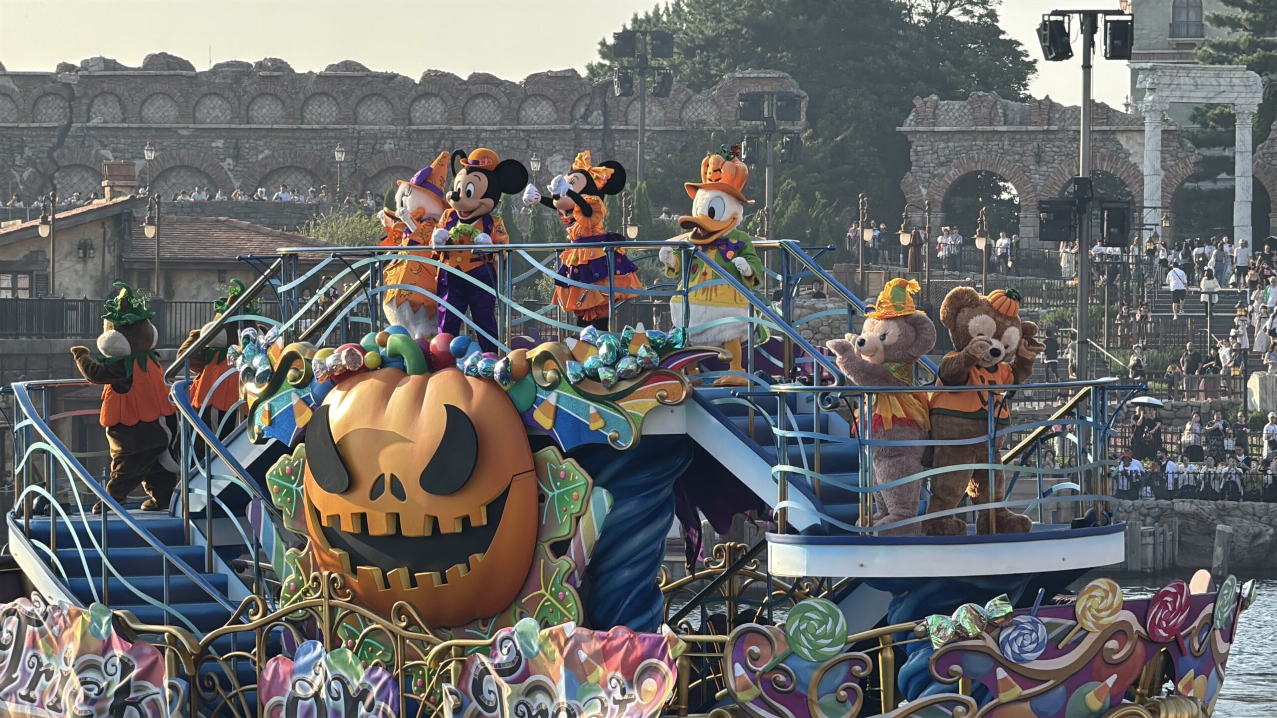Disney characters in Halloween costumes ride a float with a giant pumpkin at Tokyo Disney Resort, home to the unique Cinderella Castle.
