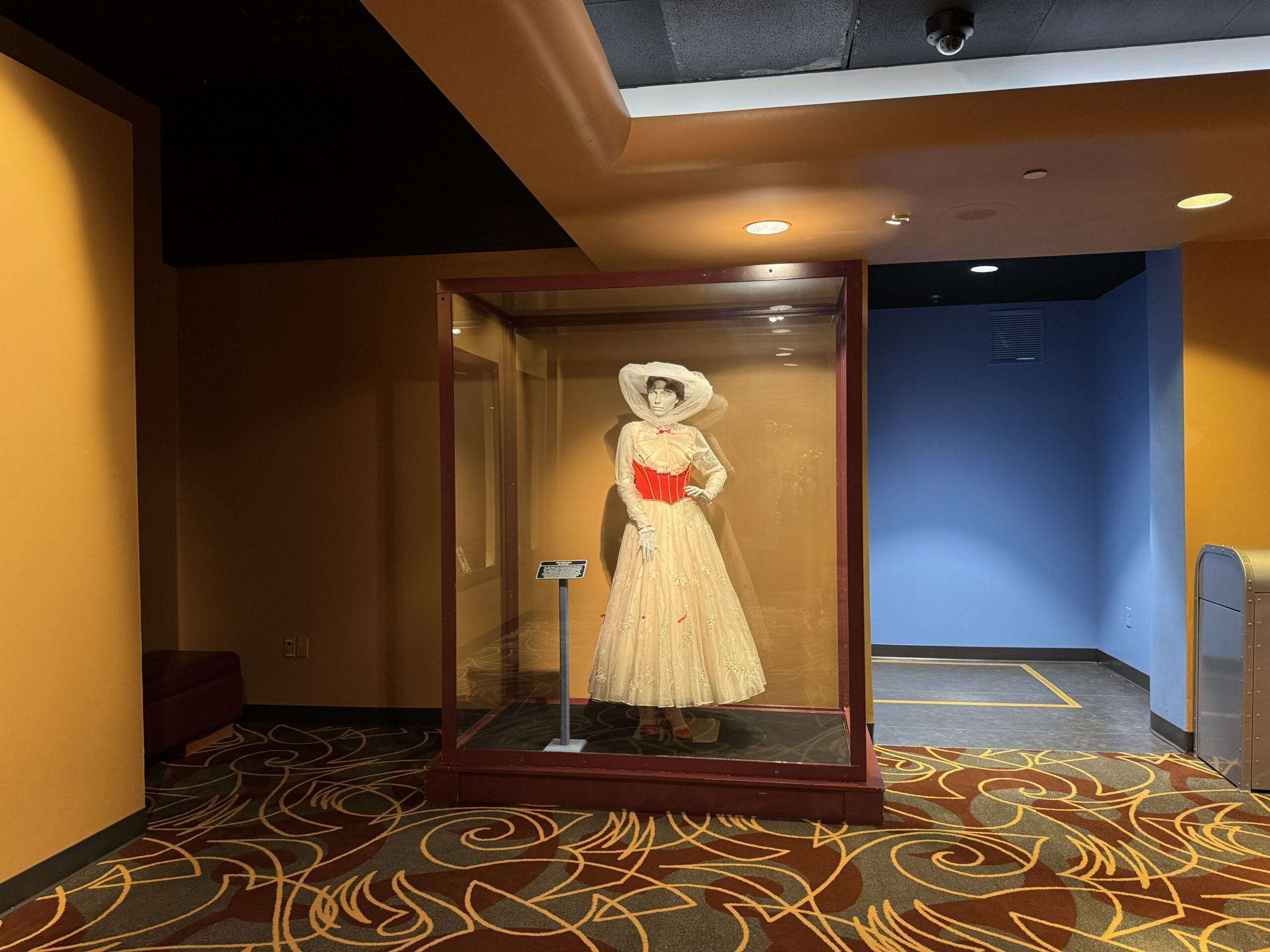 A white dress with red accents and a wide-brimmed hat in a vibrant hallway at Tokyo Disney Resort, near Cinderella Castle.