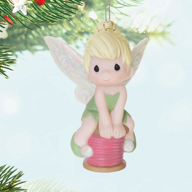 Fairy ornament with blonde hair and green wings sits on a pink spool, a magical Disney Keepsake like those found in the park shops.
