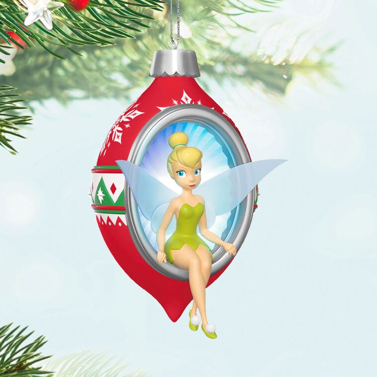 A Hallmark Tinker Bell ornament sparkles inside a red bauble on a Christmas tree, reminiscent of Main Street holiday decor at Disney Parks.