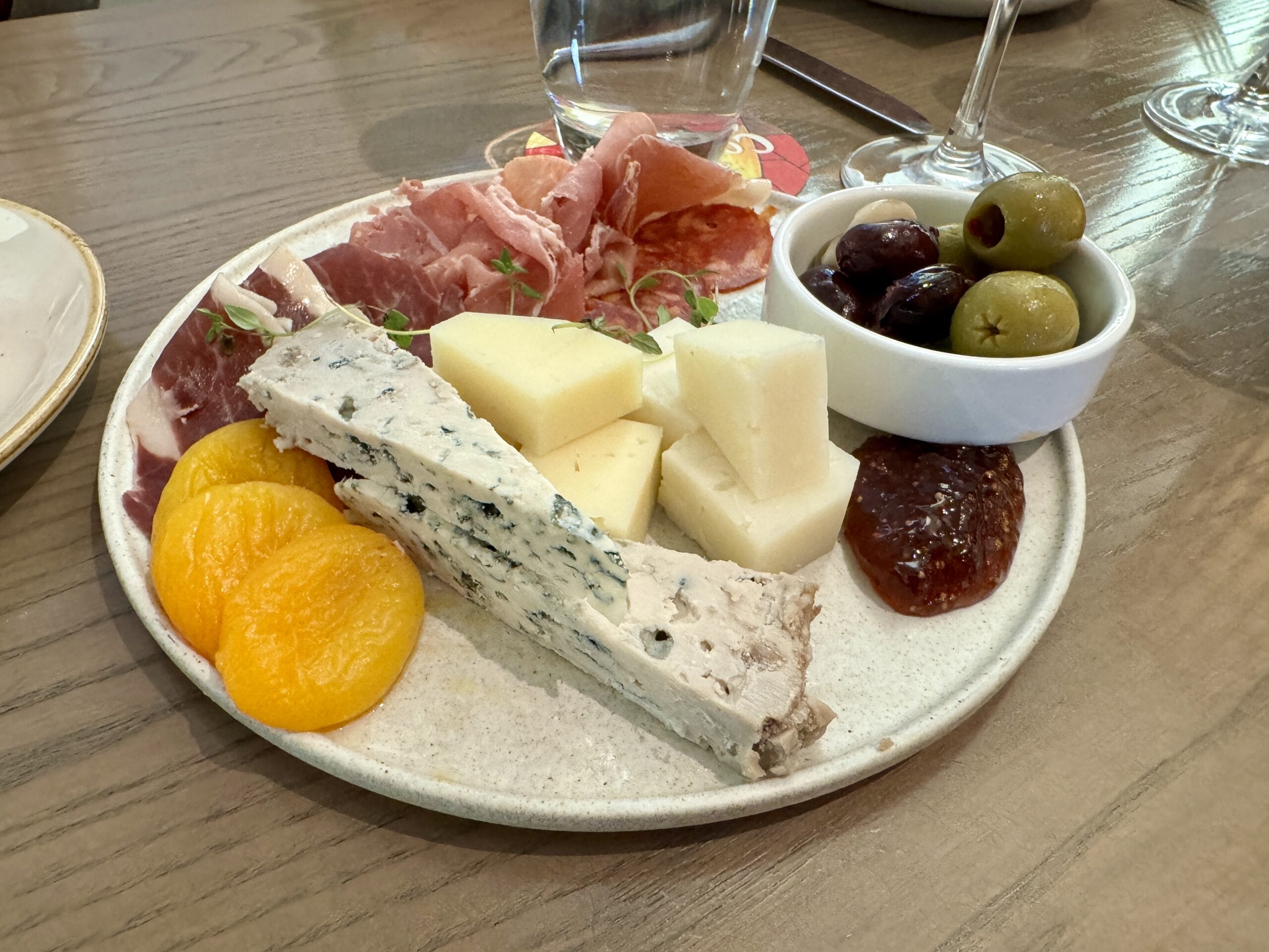 A plate with blue cheese, cubed cheese, cured meats, dried apricots, olives - Toledo - Tapas, Steak & Seafood