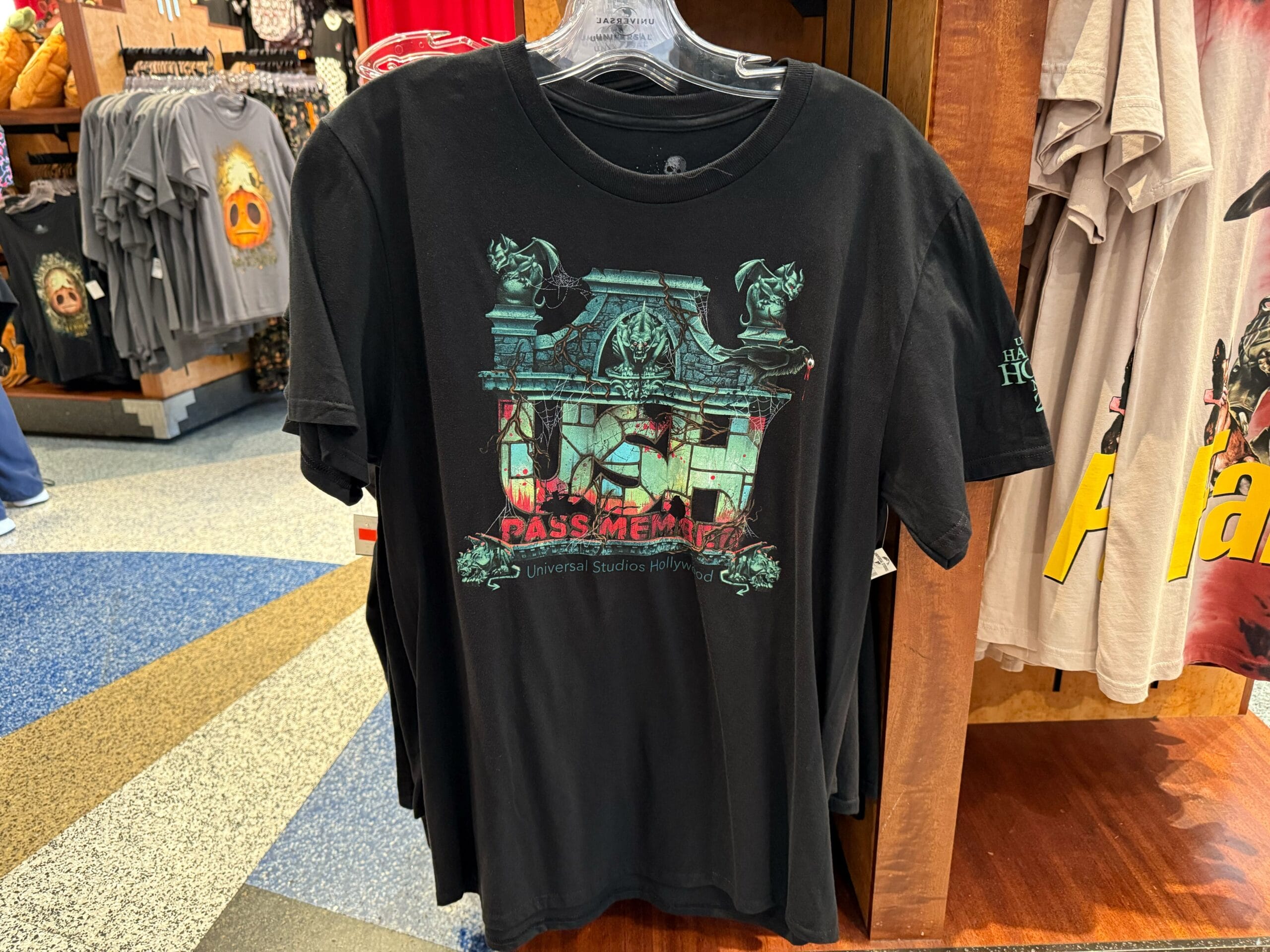 Black T-shirt with haunted conservatory and gargoyle design and “Pass Member” text, 2025 Halloween Horror Nights item.