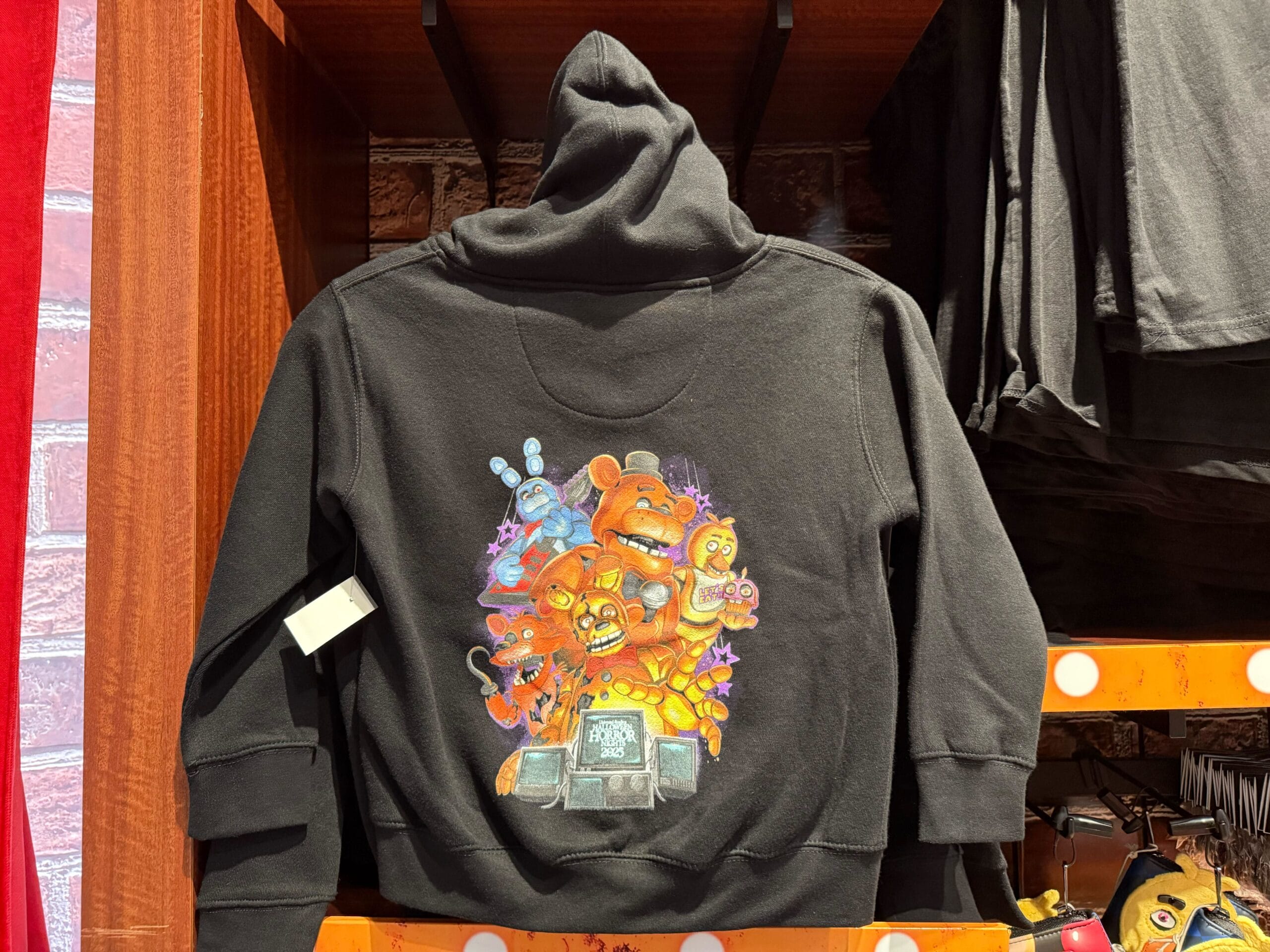 Black hoodie with colorful "Five Nights at Freddy's" characters graphic on the back, 2025 Universal Studios merch.