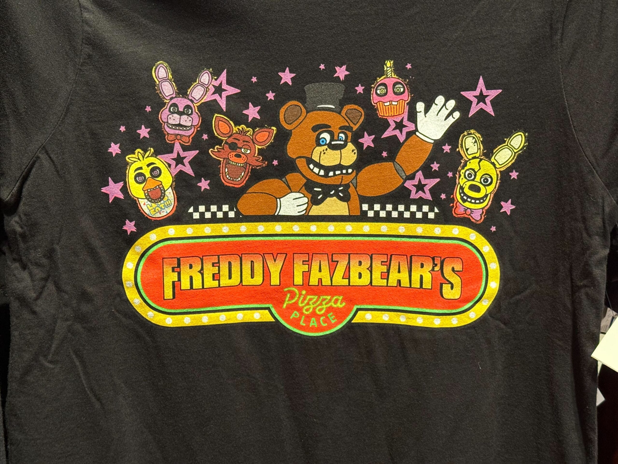 Black T-shirt with Freddy Fazbear’s Pizza Place logo and cartoon icons of the animatronics with pink stars.