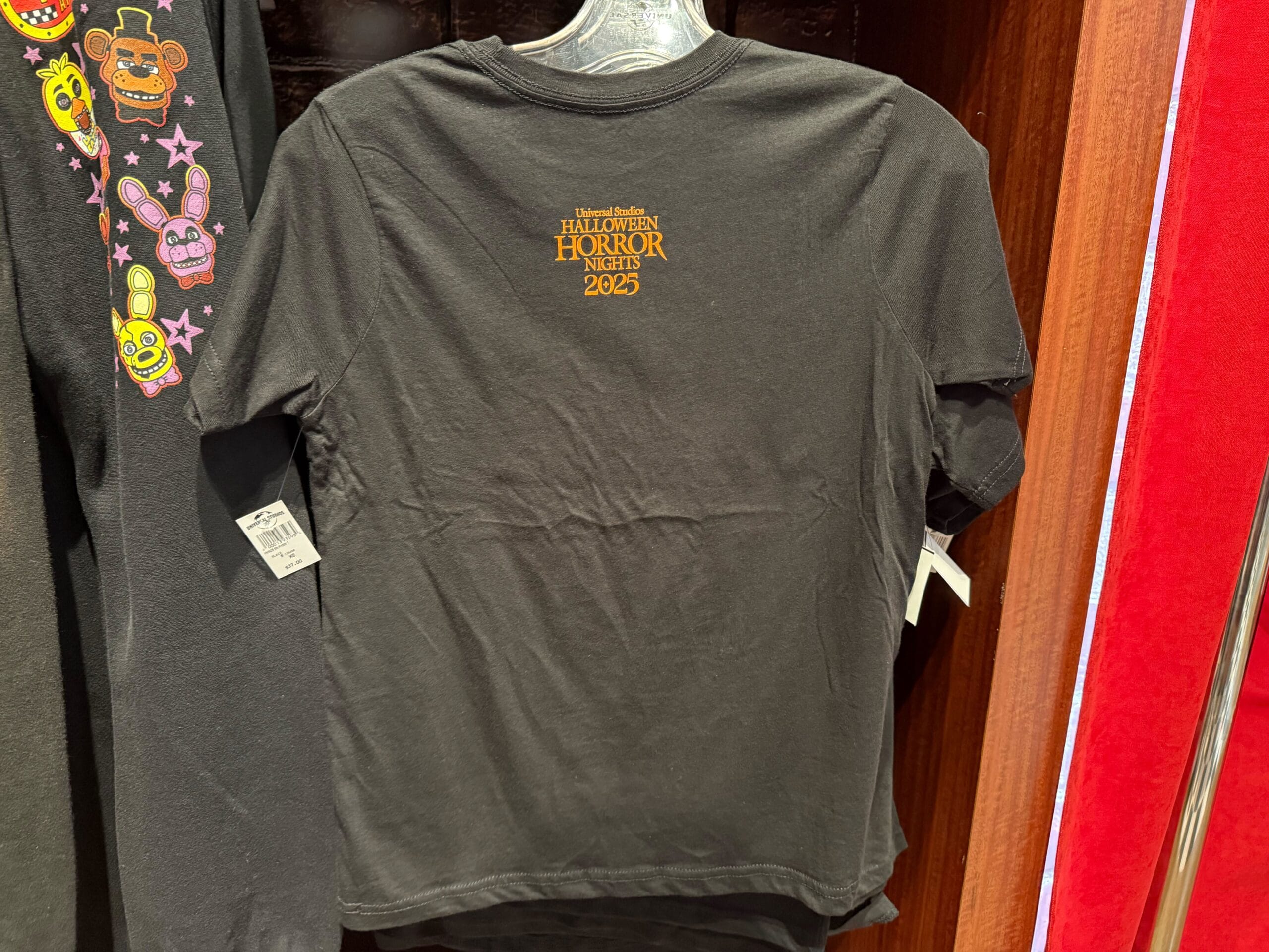 A black t-shirt on a hanger with "Universal Studios Halloween Horror Nights 2025" in red.