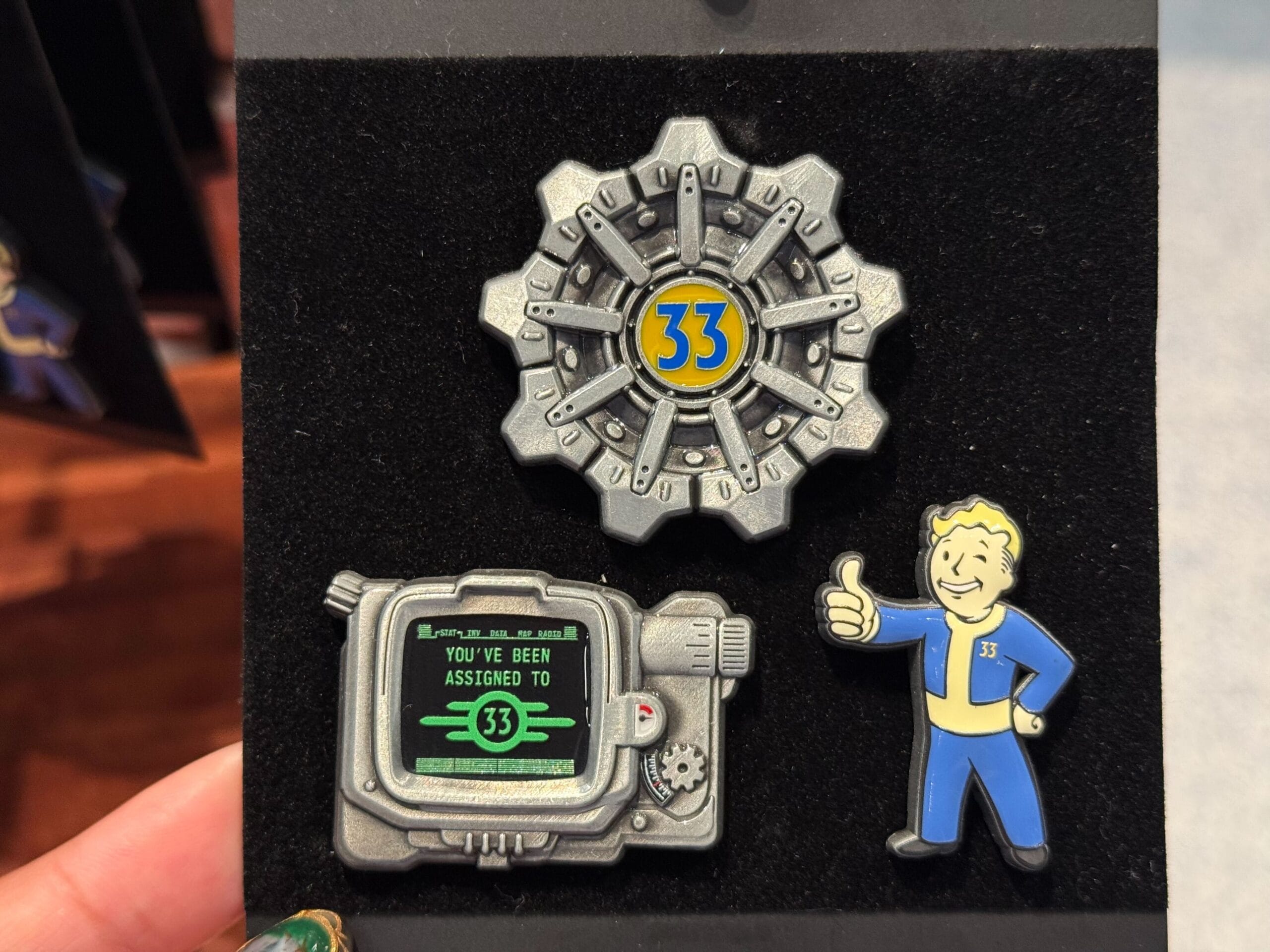 Three Fallout pins on a Universal Studios display card: Vault 33 gear, Pip-Boy, and Vault Boy.