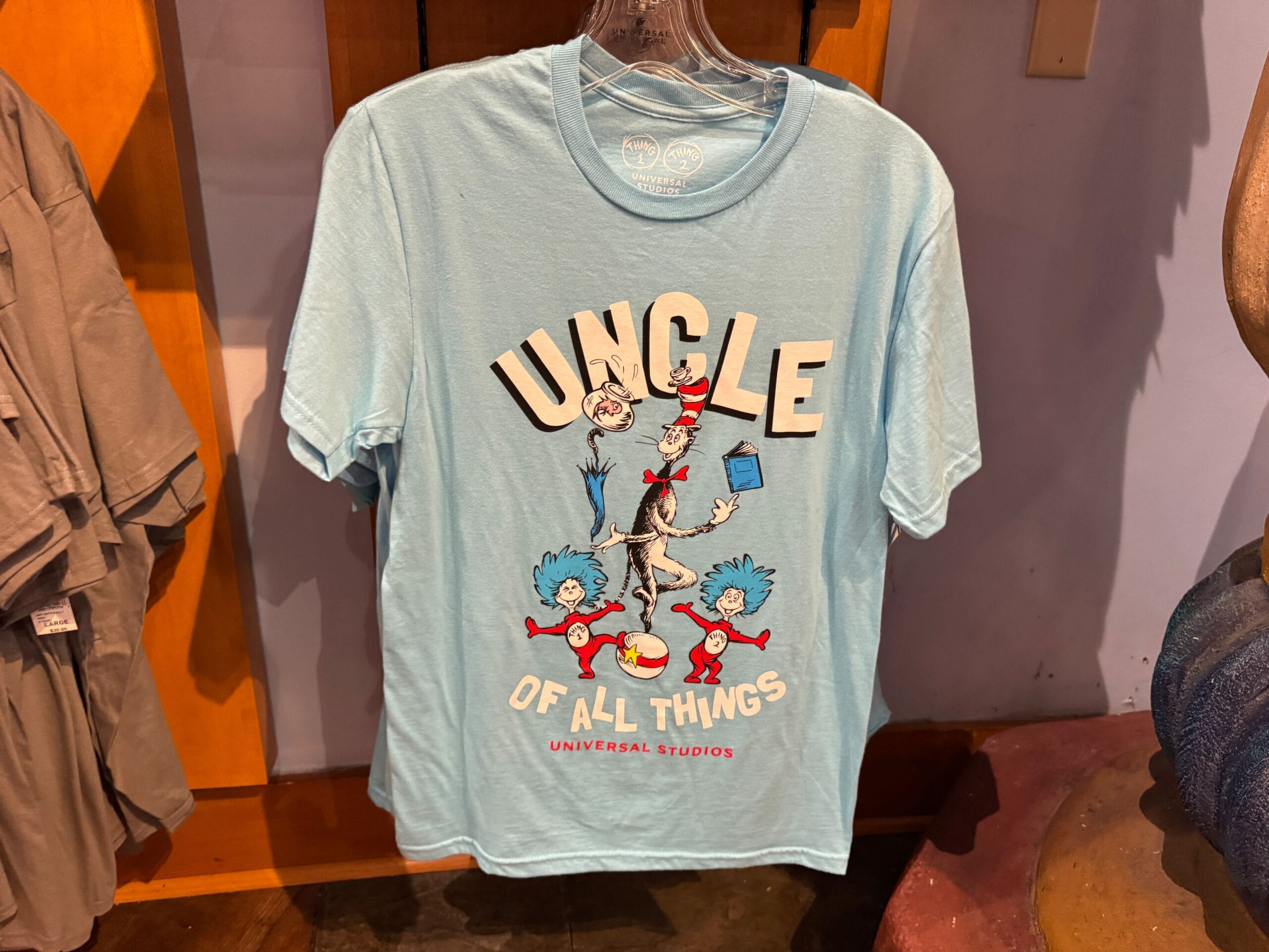 Light blue Dr. Seuss T-shirt featuring Cat in the Hat, Thing 1 and Thing 2, and "Uncle of All Things"—not a Disney Parks castle.