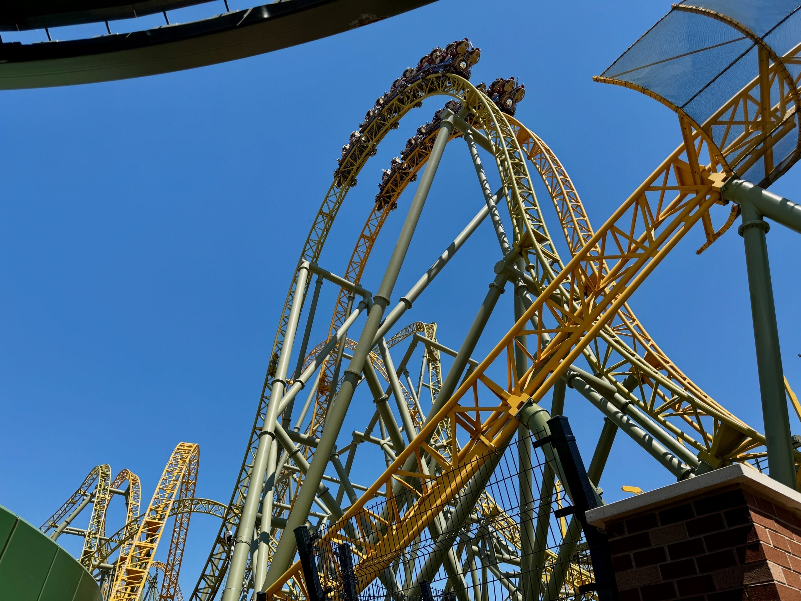 Riders on the yellow Stardust Racers roller coaster loop high under the sunny sky at Epic Universe’s grand reopening.